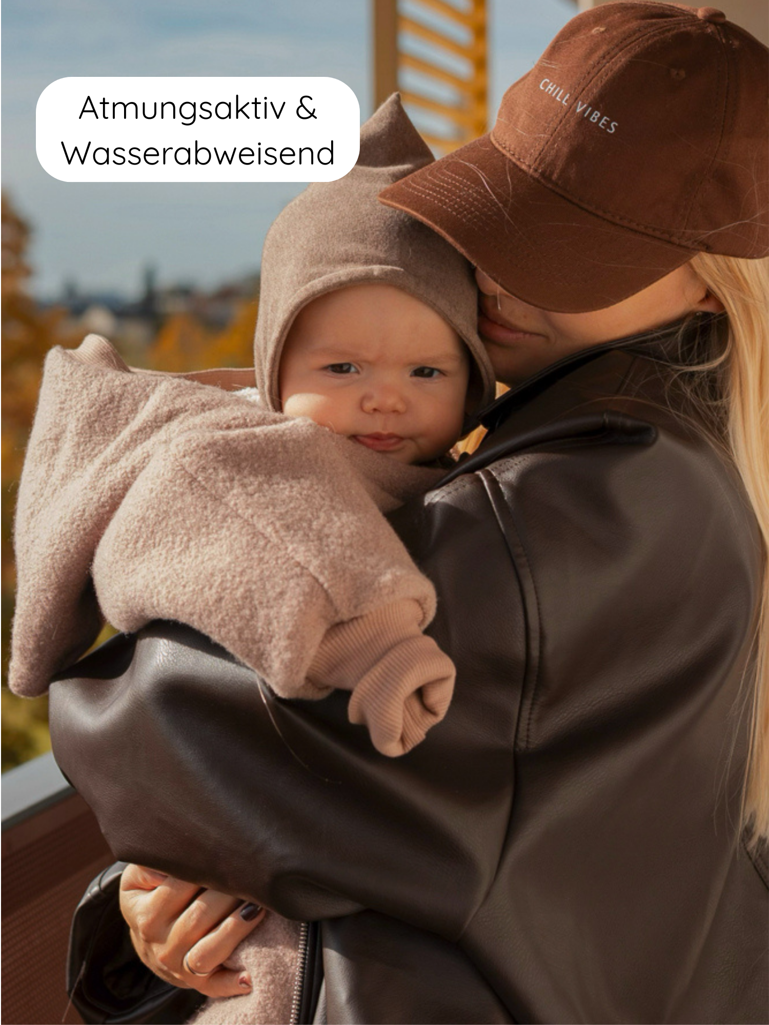 Erwachsene Person hält Kind im Winter Wollwalk Overall mit Teddyfutter-Puder, atmungsaktiv und wasserabweisend, auf Balkon, umgeben von herbstlicher Kulisse.