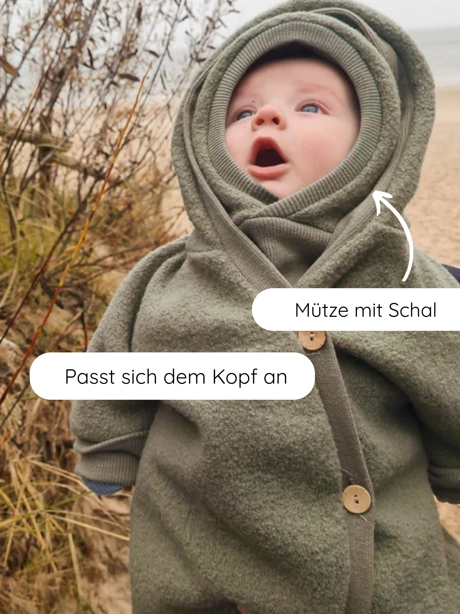 Kleinkind am Strand in einem olivegrünen Schlupfmütze Wollwalk - Pistazie, mit Kapuze und integriertem Schal, perfekt anliegend und schützend, ideal für kalte Tage.