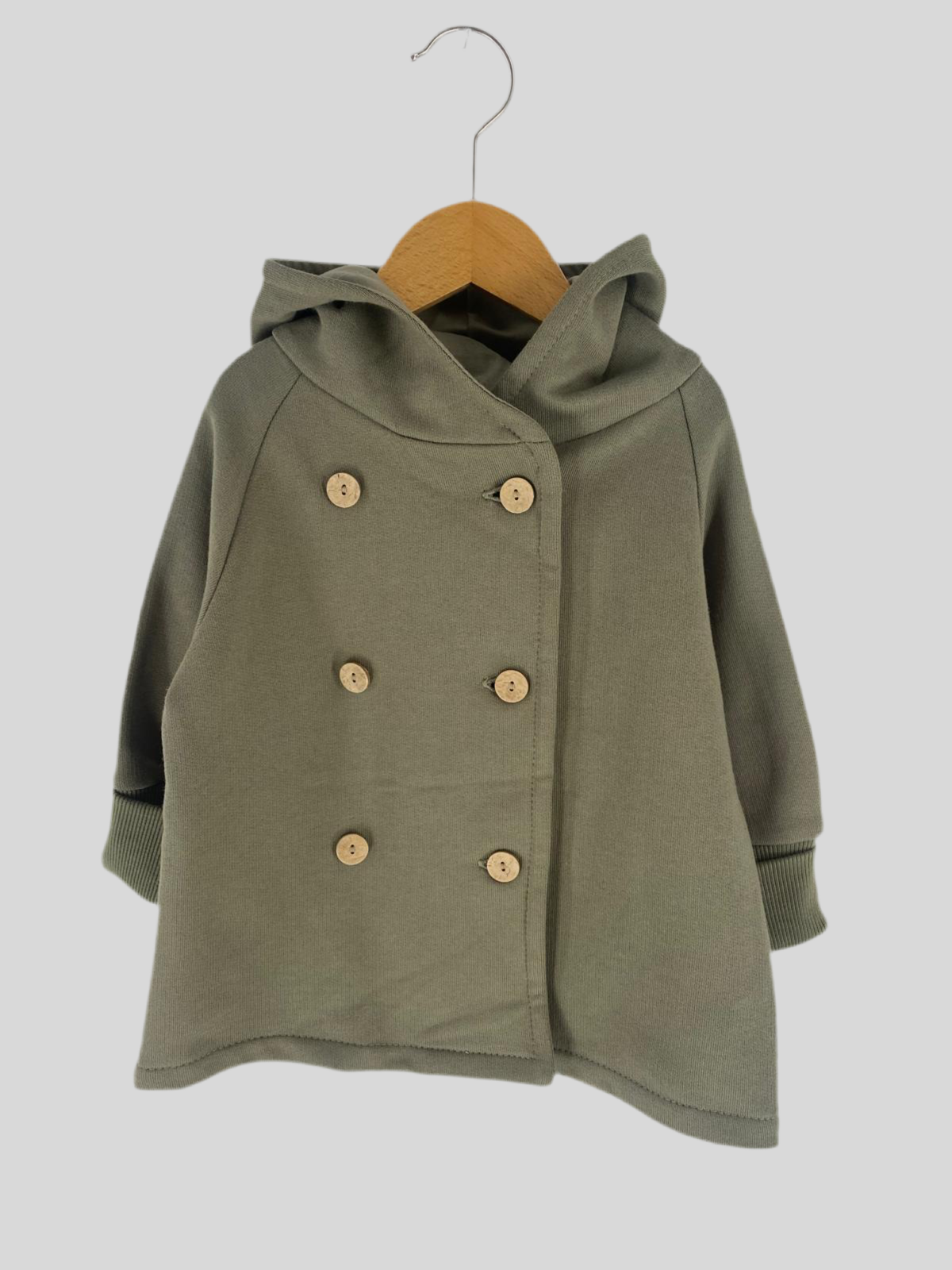 NEU Wichteljacke Zweireiher Bio-Sweat Pistazie Gr 1Y auf einem Bügel. Detaillierte Nahaufnahme zeigt den Stoff und Knöpfe, präsentiert auf einem Holzuntergrund für modischen äußeren Eindruck. Zustand: neu.