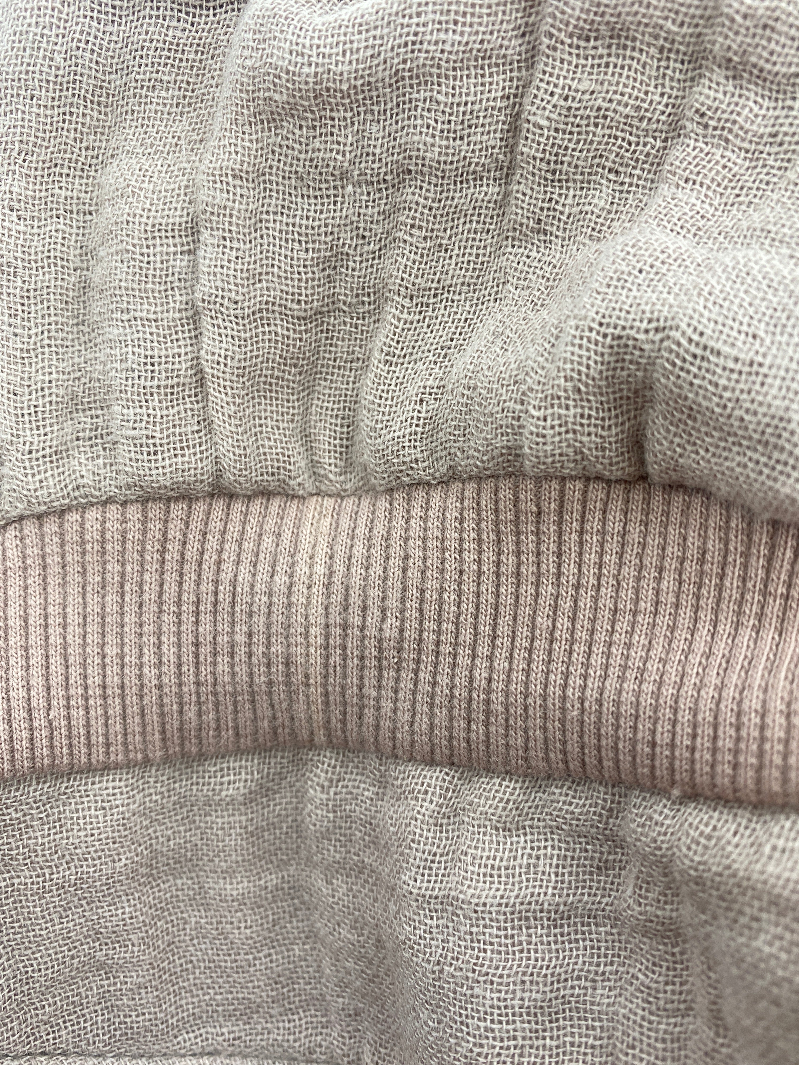 Mütze Michelmütze Musselin Puder mit Nackenschutz Gr 2Y-4Y, zeigt naturfarbenes, locker gewebtes Leinen und ein horizontal verlaufendes, geripptes Bündchen in Puder mit kleinem Stofffehler auf der Vorderseite.