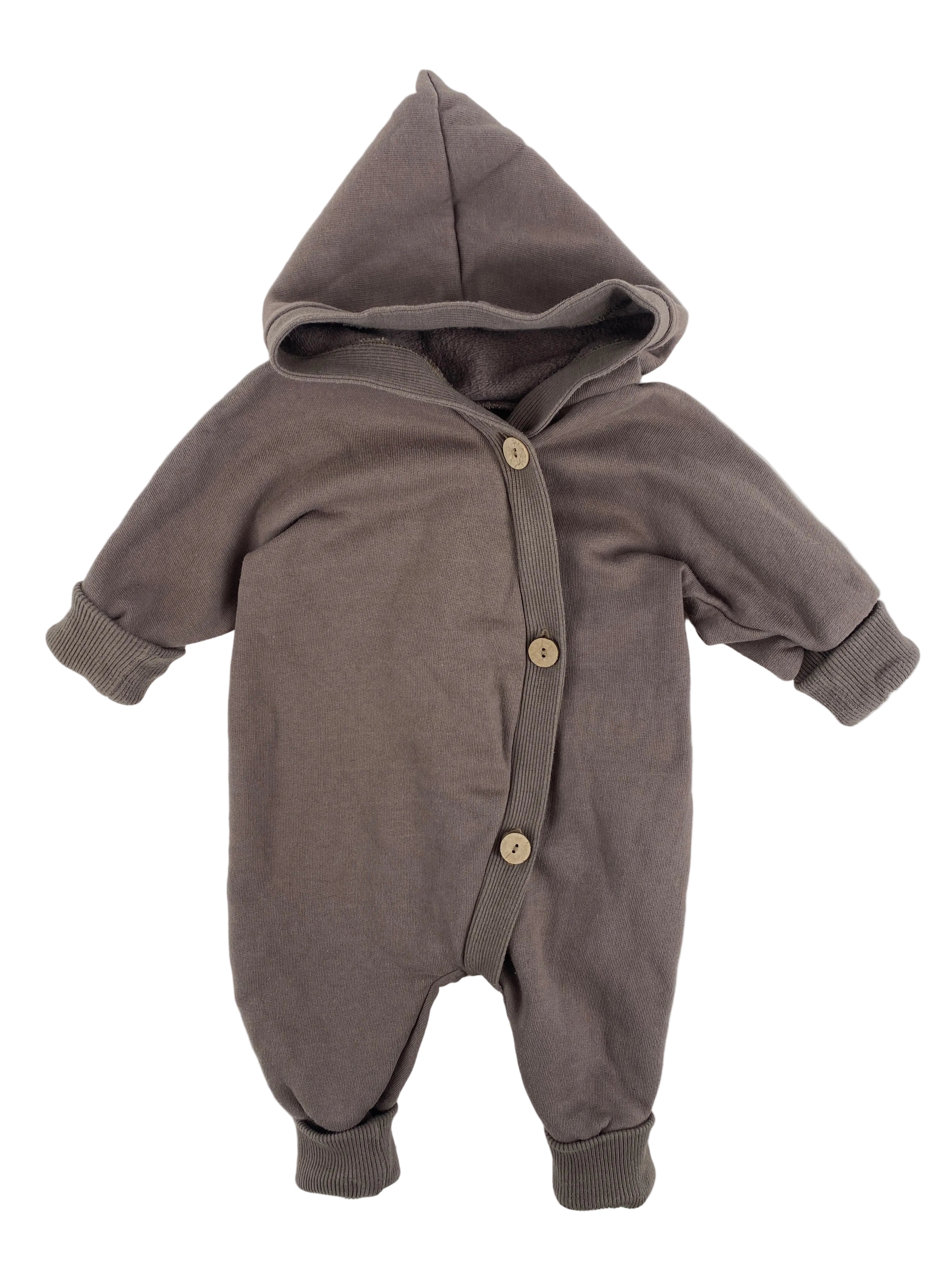 Ein kuscheliger Kuschelanzug Bio Sweat Praline Gr 0M, ein einteiliger Babystrampler mit Kapuze, langen Ärmeln, integrierten Fußmanschetten und einer Knopfleiste vorne, in sehr gutem Zustand.