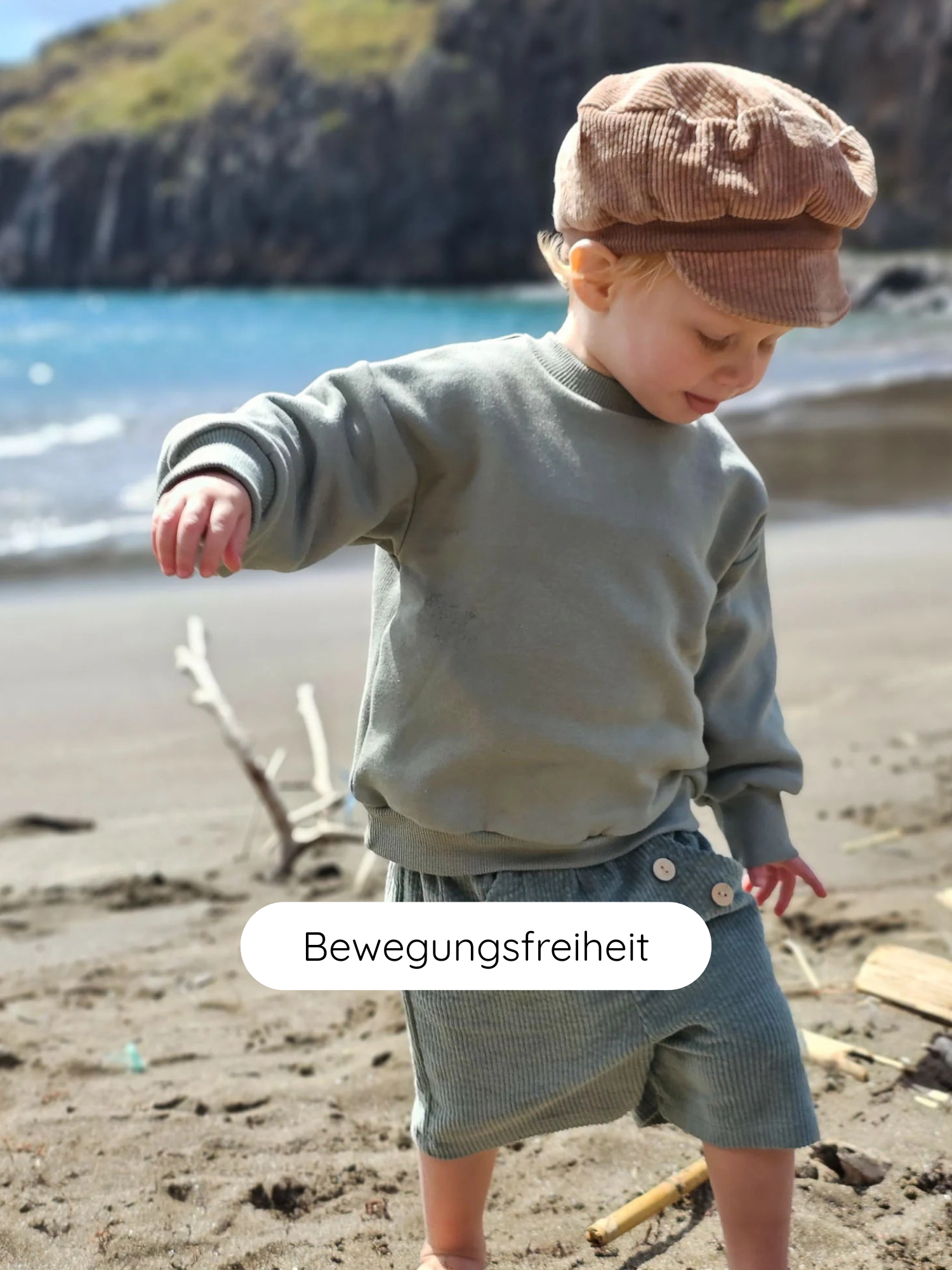 Kleinkind in Pulli Bio-Sweat - Aqua spielt am Strand. Der Pulli ist locker geschnitten, aus weichem, atmungsaktivem Bio-Sweatstoff und bietet viel Bewegungsfreiheit.