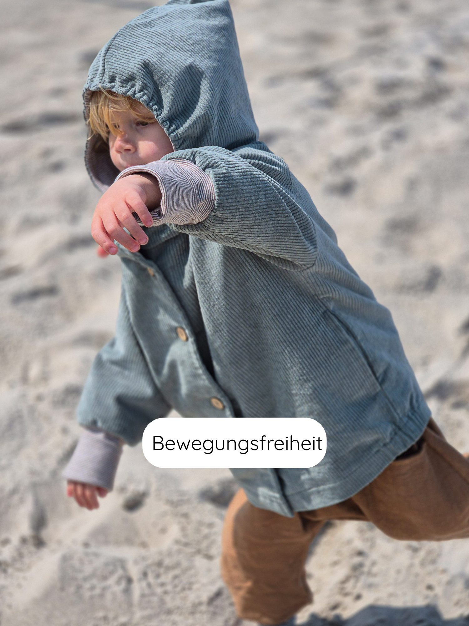 Kleinkind in Wichteljacke Breitcord Stretch- Aqua mit süßer Wichtelkapuze und Ringel-Armbündchen, spielt auf Sand. Jacke bietet Bewegungsfreiheit und wächst dank krempelbarer Bündchen mit.