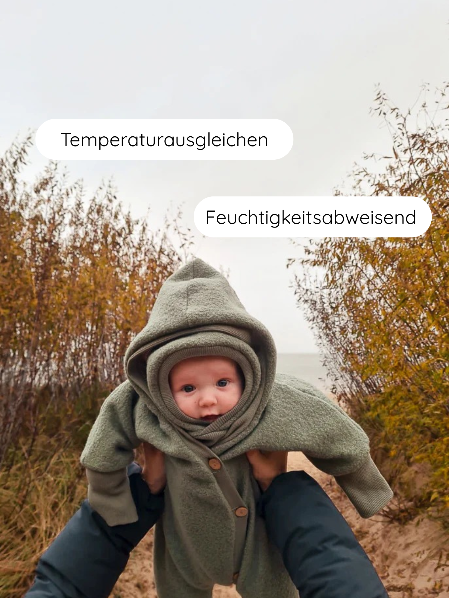 Kleines Baby in einem weichen, moosgrünen Schlupfmütze Wollwalk - Pistazie, das von Erwachsenen gehalten wird. Der Einteiler ist temperaturausgleichend und feuchtigkeitsabweisend, ideal für kühlere Tage.