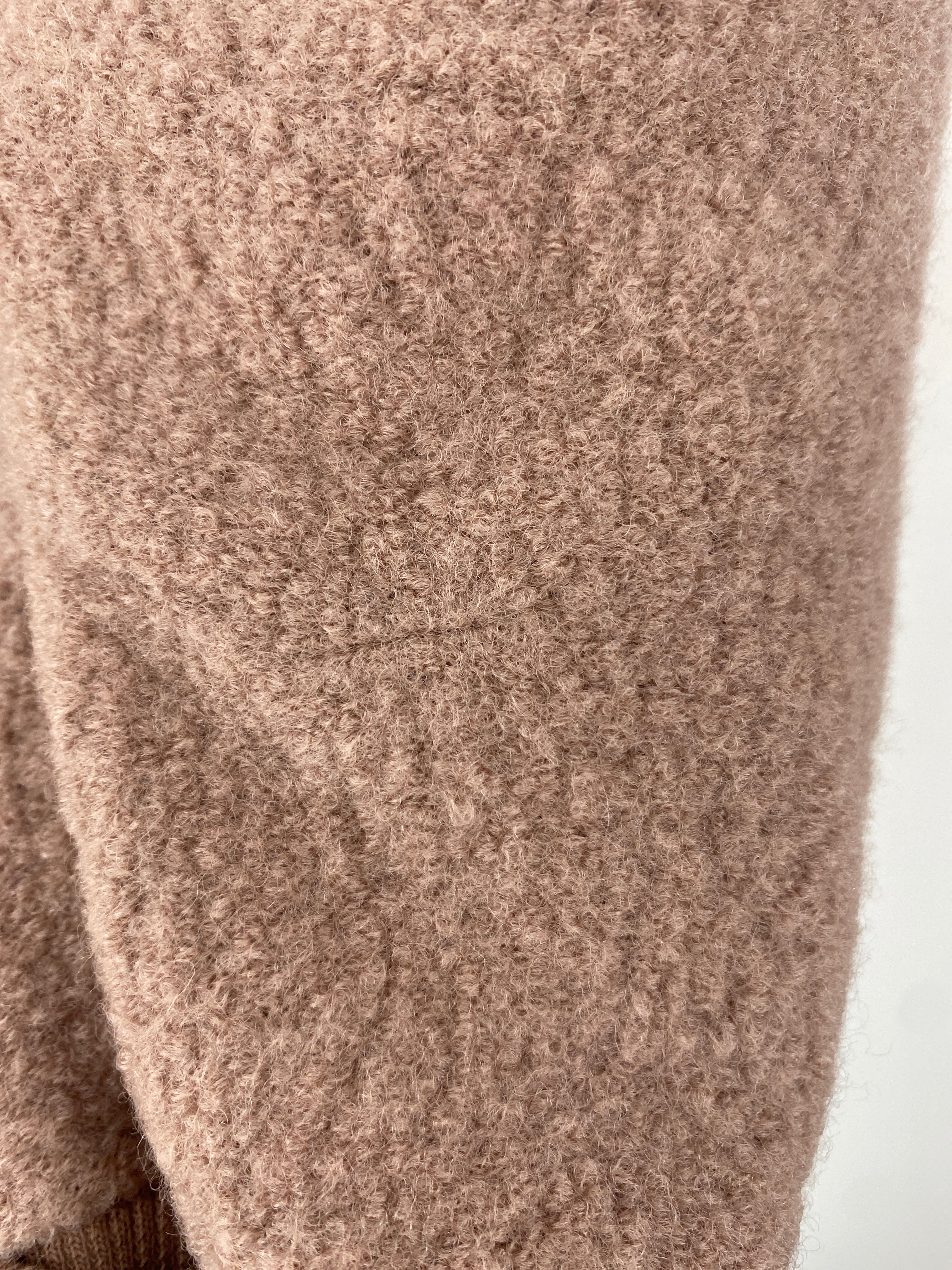 Nahaufnahme eines flauschigen Strickstoffs, vermutlich vom Ärmel des Kopie Kuschelanzug Wollwalk Puder Gr 6M, mit weicher Textur, leichtem Woll- oder Alpakamischgewebe. Zustand: neu, kleiner Stofffehler hinten.
