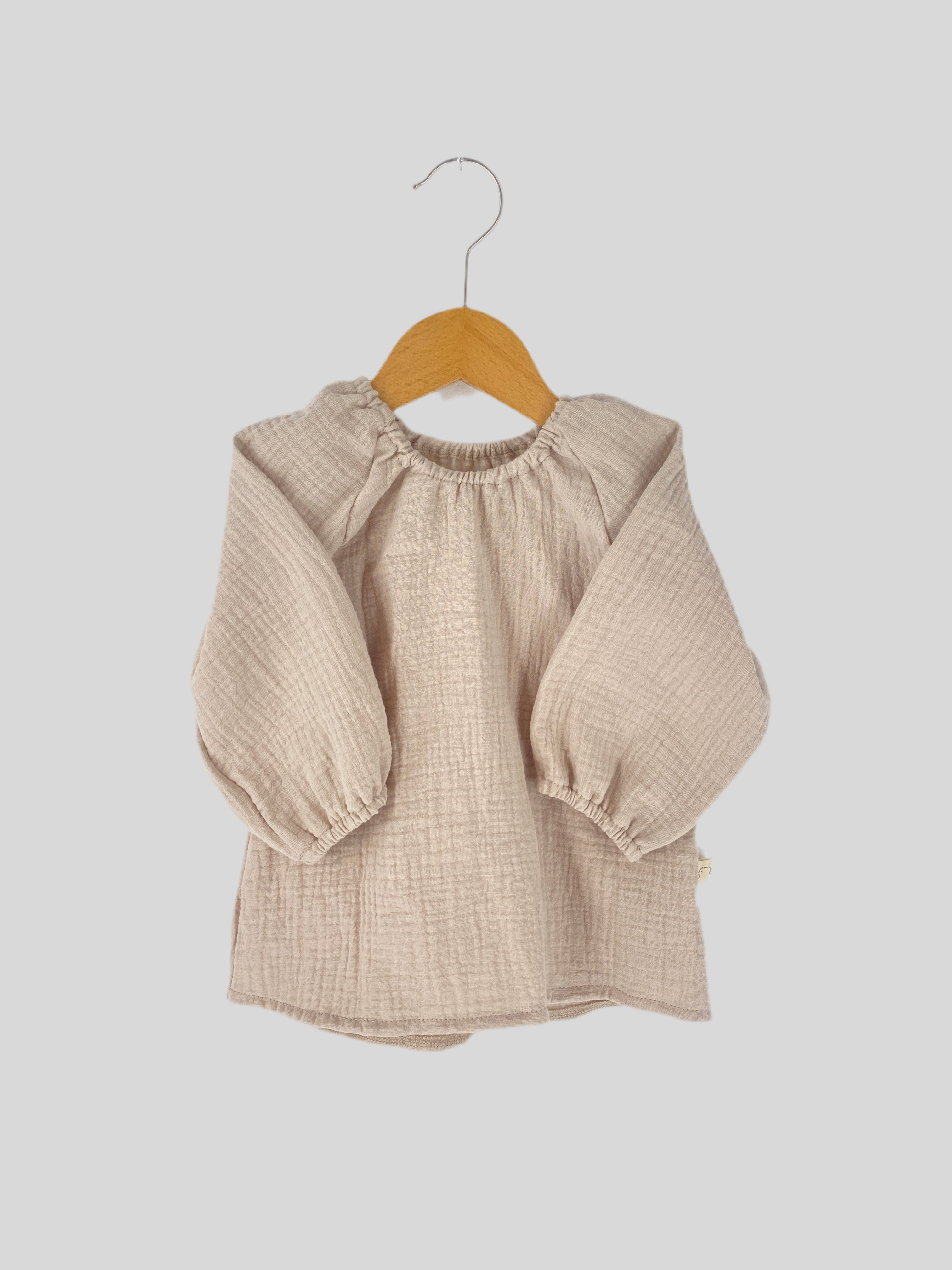 Blüschen Musselin Sand Gr. 1Y, neu. Leichtes Musselin-Material mit zarten Falten und weichem Fall, ideal für Kleinkinder. Perfekt für einen luftigen und bequemen Tragekomfort.