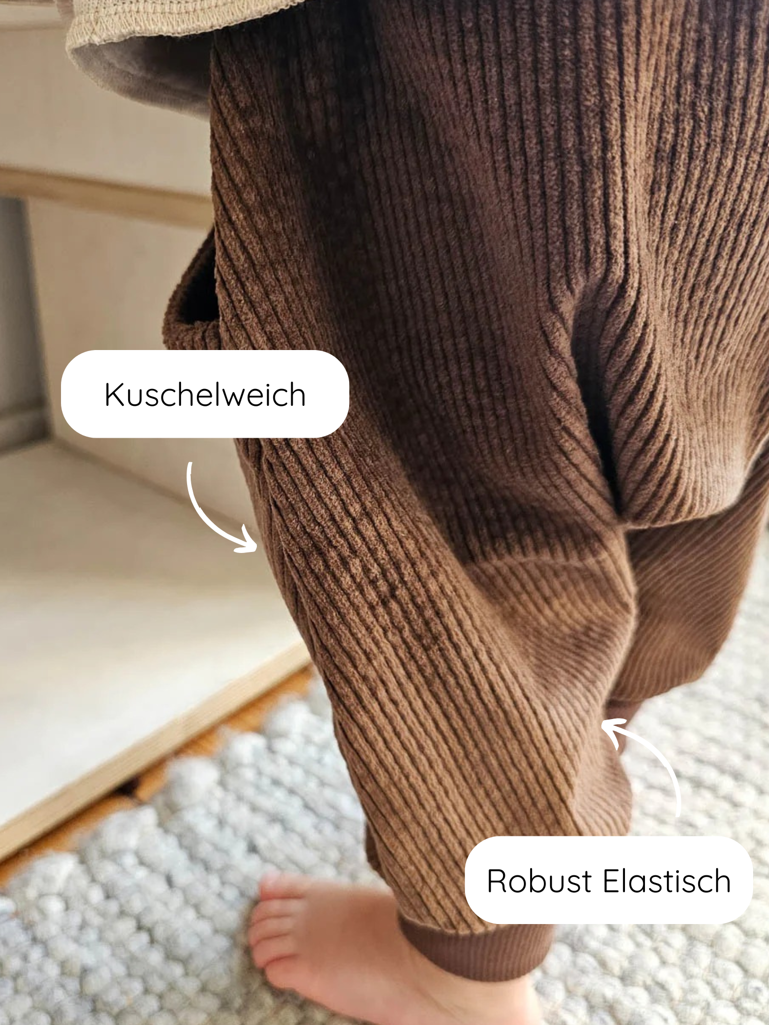 Knickerbocker Breitcord - Schoko: Detailaufnahme der Beine und Füße eines Kindes in weicher, gerippter Cordhose mit Känguru-Tasche und elastischem Knöchelbündchen, stehend auf Teppich.
