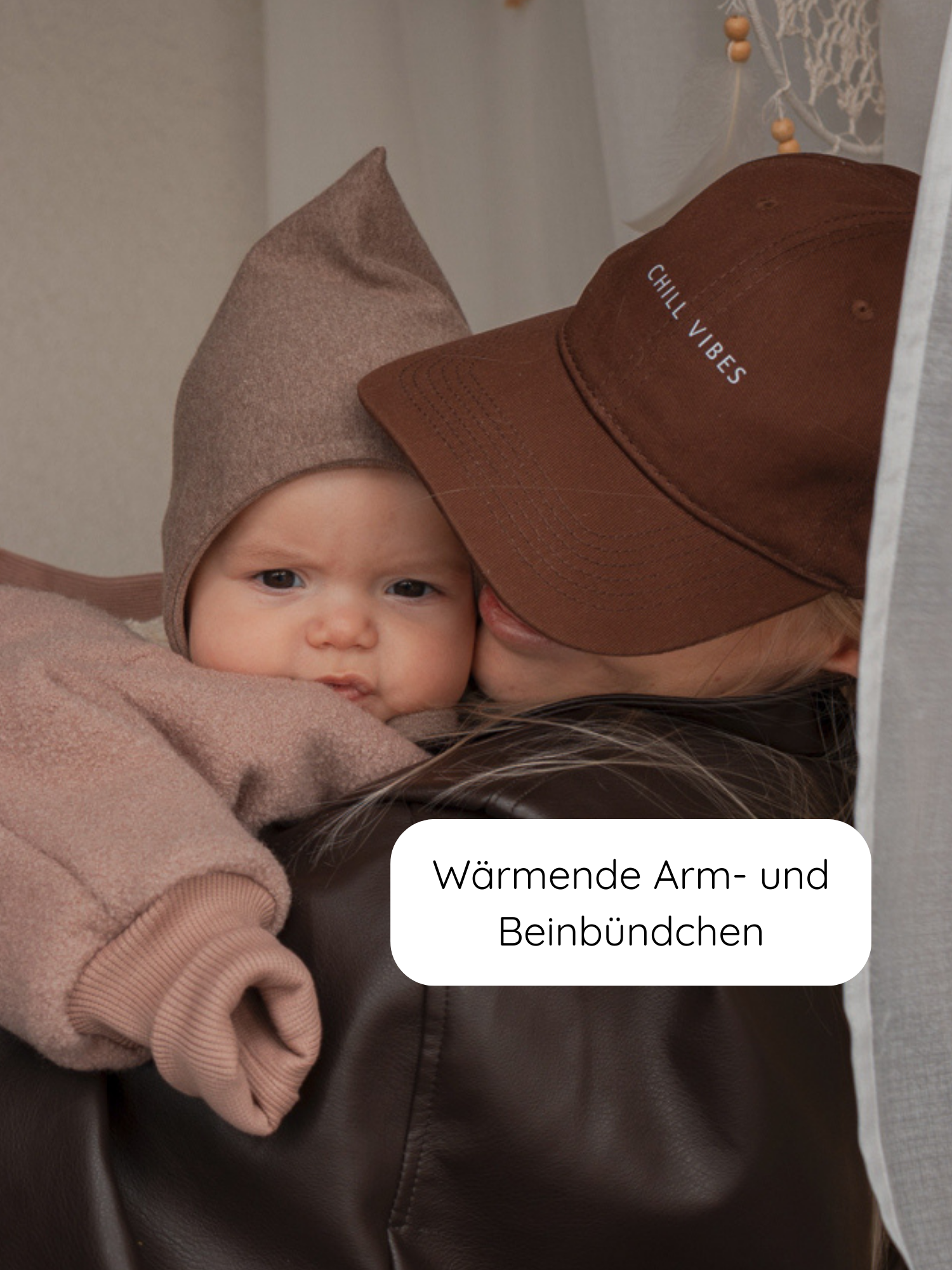 Kleinkind im Winter Wollwalk Overall mit Teddyfutter - Puder, mit spitzer Kapuze und gerippten Bündchen, wird von einem Erwachsenen mit brauner Kapuze CHILL VIBES gehalten.