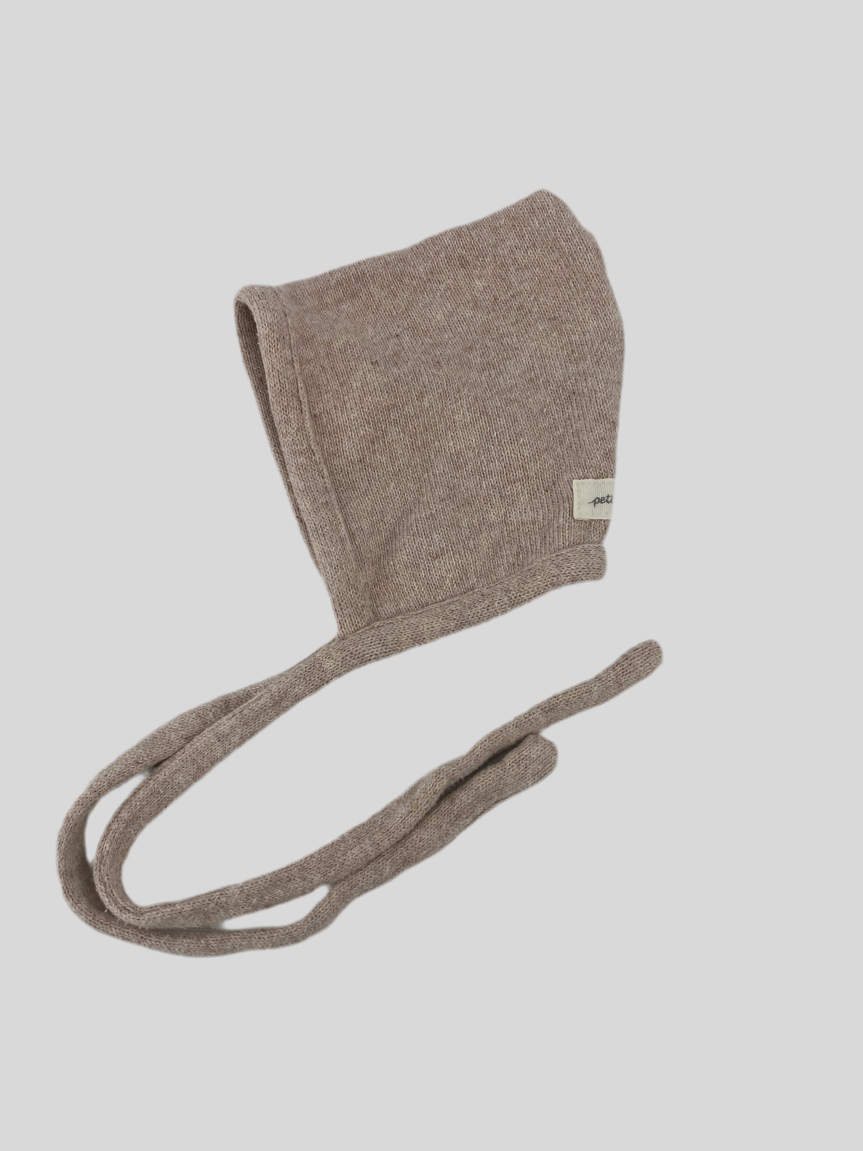 Nahaufnahme der (Kopie) Zwergenmütze Strick Sand Gr 3M, zeigt detailliert das gestrickte Muster und das Stoffetikett, betont die hochwertige Verarbeitung und den sehr guten Zustand der modischen Accessoire-Mütze.
