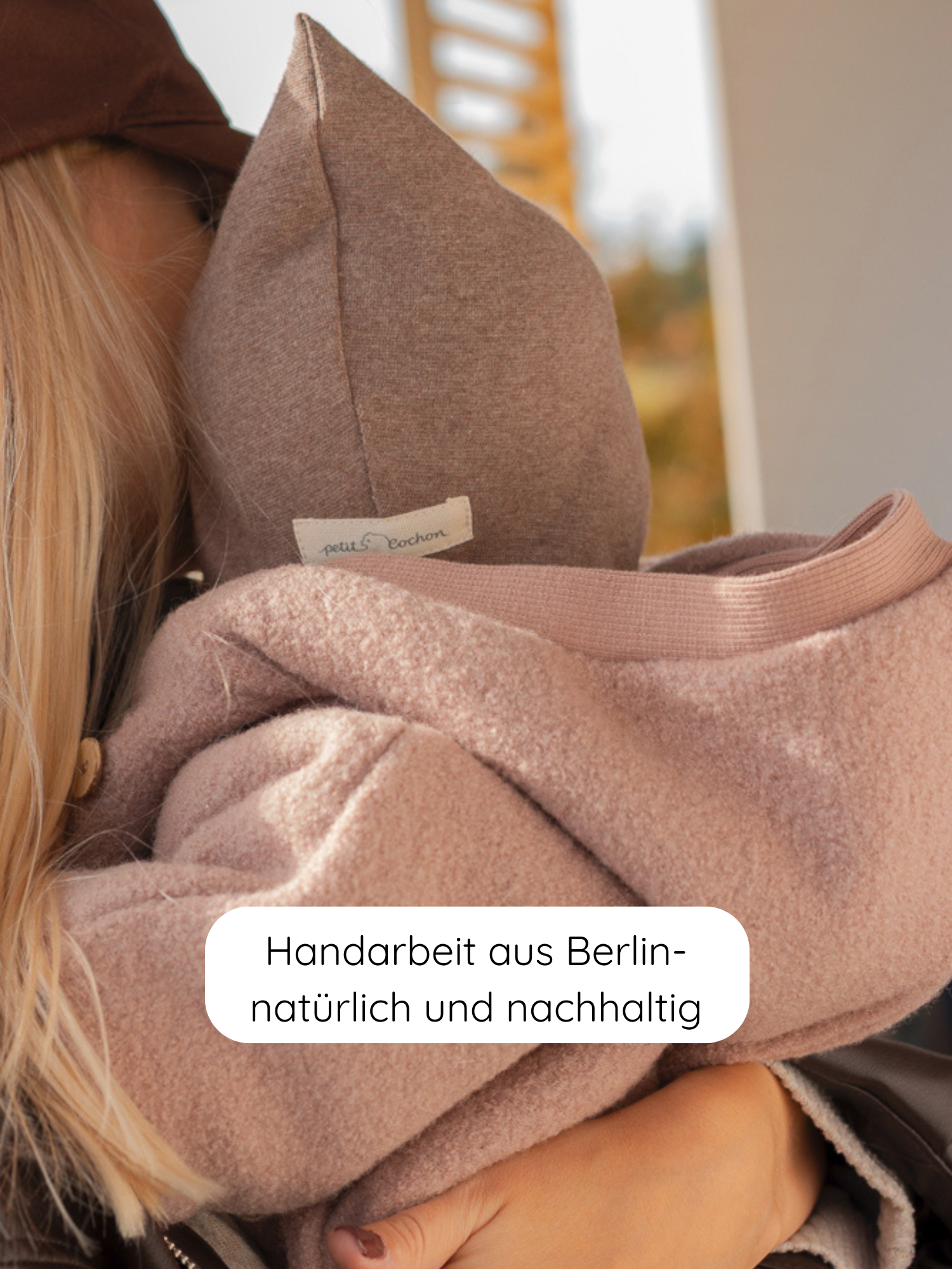 Winter Wollwalk Overall mit Teddyfutter-Puder: Ein Kind in natürlichem Wollwalk-Overall mit Teddyfutter, ausgestattet mit brauner Kapuze. Handarbeit aus Berlin, natürliche Materialien für kalte Wintertage.