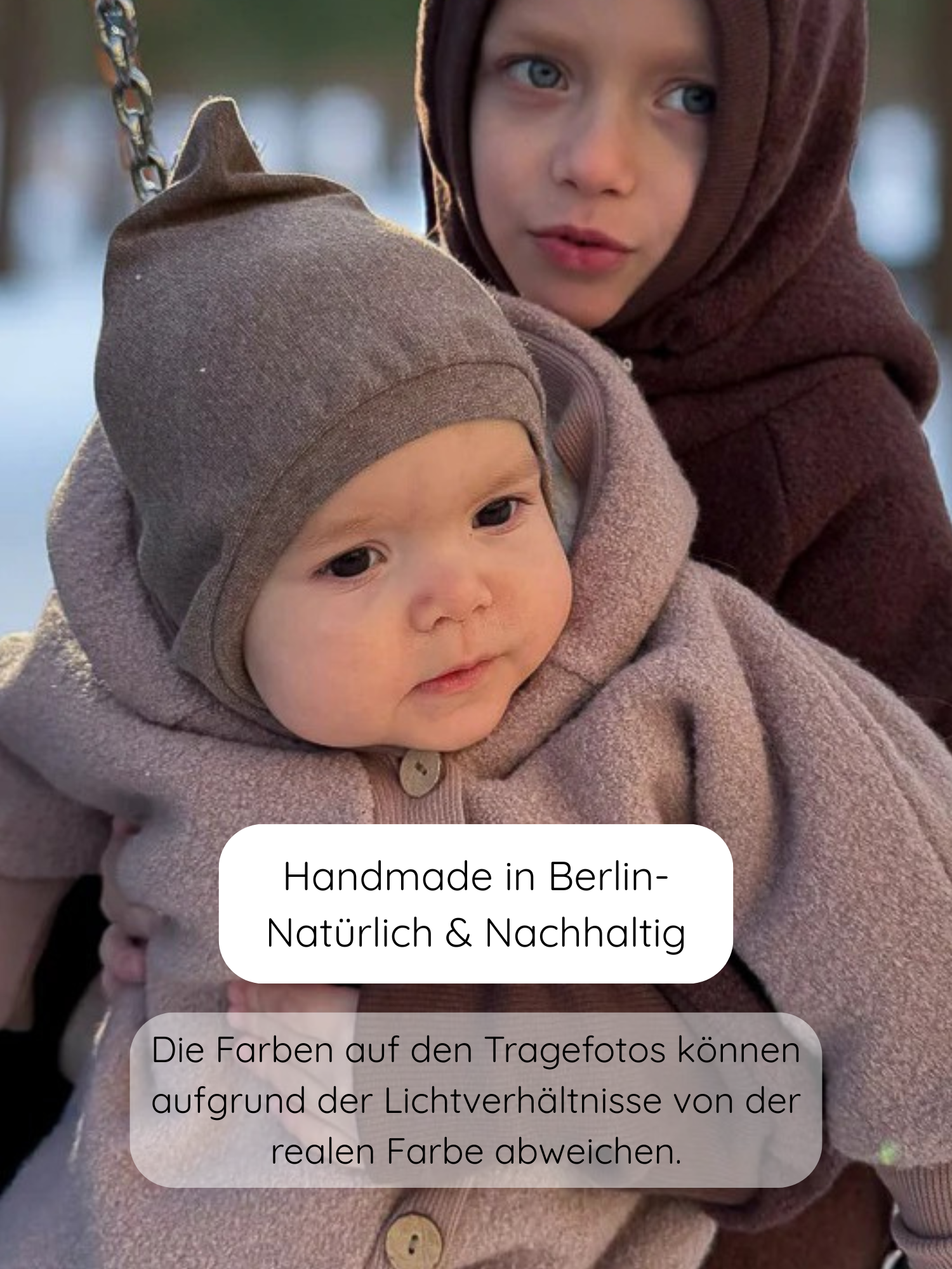 Zwei Kinder im Schnee, das vordere trägt eine Schlupfmütze Feinstrick-Jersey in Hafer Meliert. Die Mütze schützt Kopf, Ohren und Hals, ideal für kalte Tage.