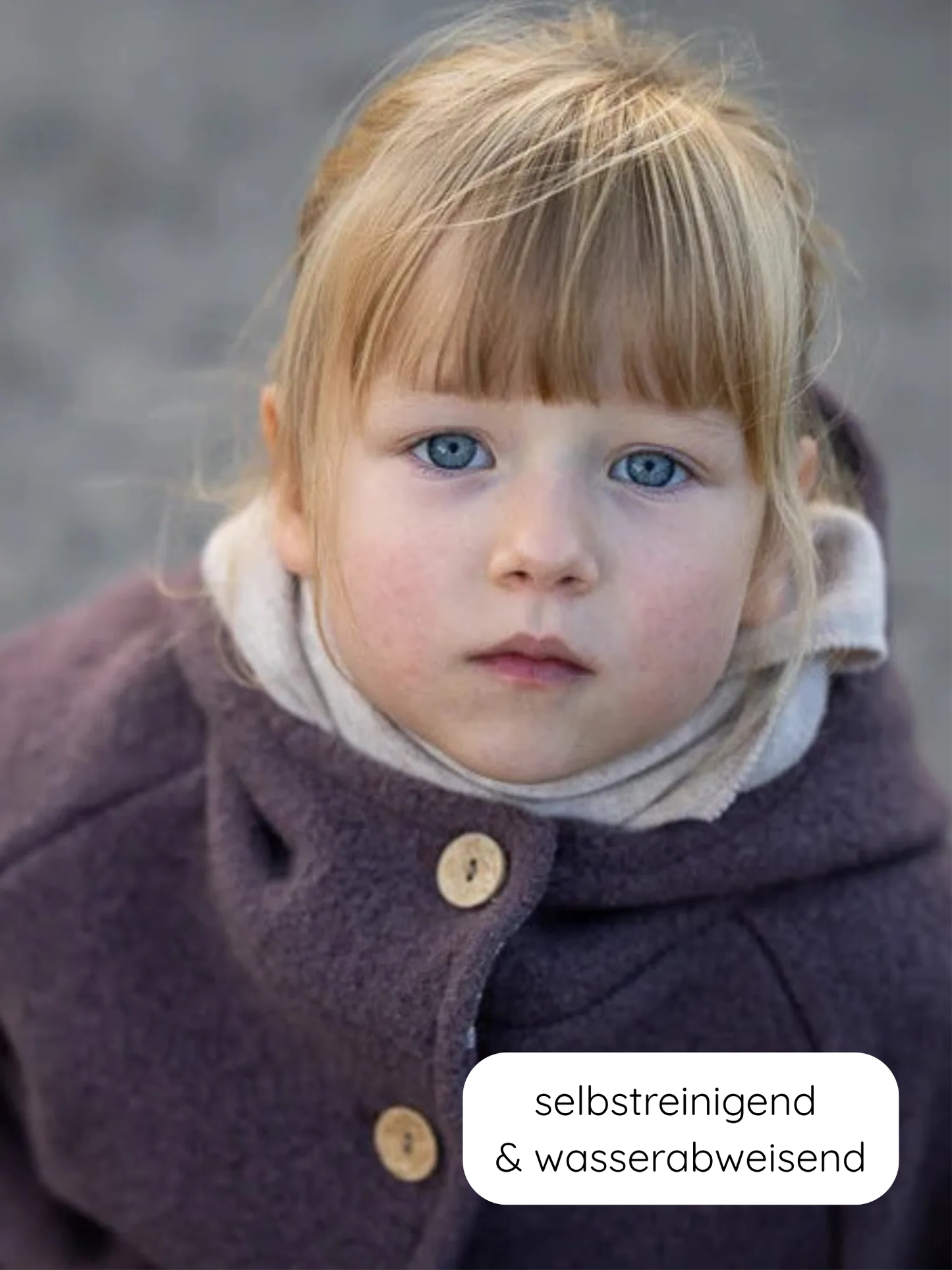 Kleinkind trägt Wollwalk-Wichteljacke Malve mit Bio-Jersey-Futter, dunkler Mantel über hellem Rollkragen. Label selbstreinigend & wasserabweisend sichtbar. Perfekt für kühles Wetter, handgemacht in Berlin.