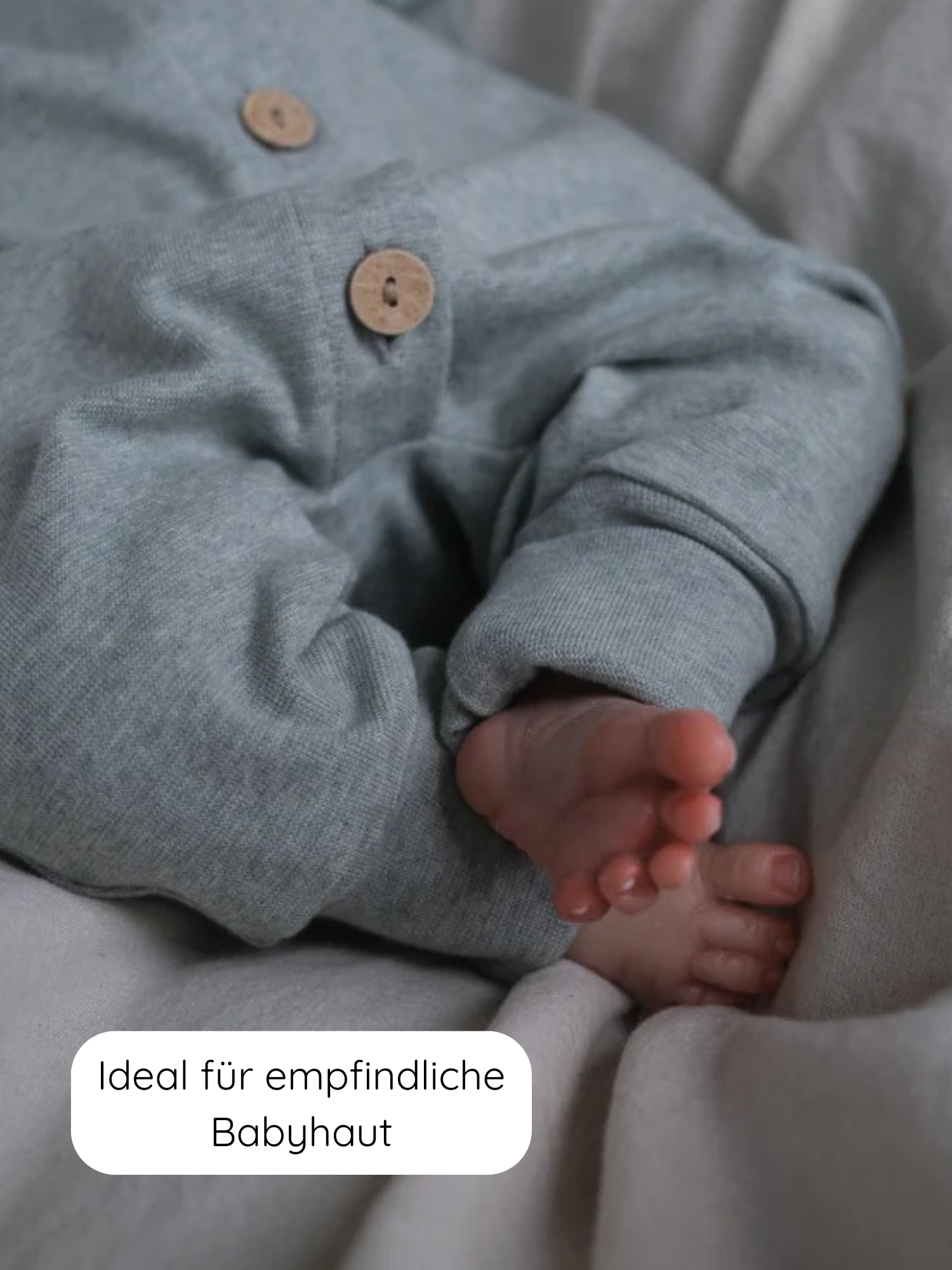 Nahaufnahme eines Babybeins in einem weichen, grauen Mini Overall Feinstrick - Mint Meliert mit Knöpfen, ideal für empfindliche Babyhaut, gefertigt aus meliertem Feinstrick-Jersey für Komfort und Bewegungsfreiheit.