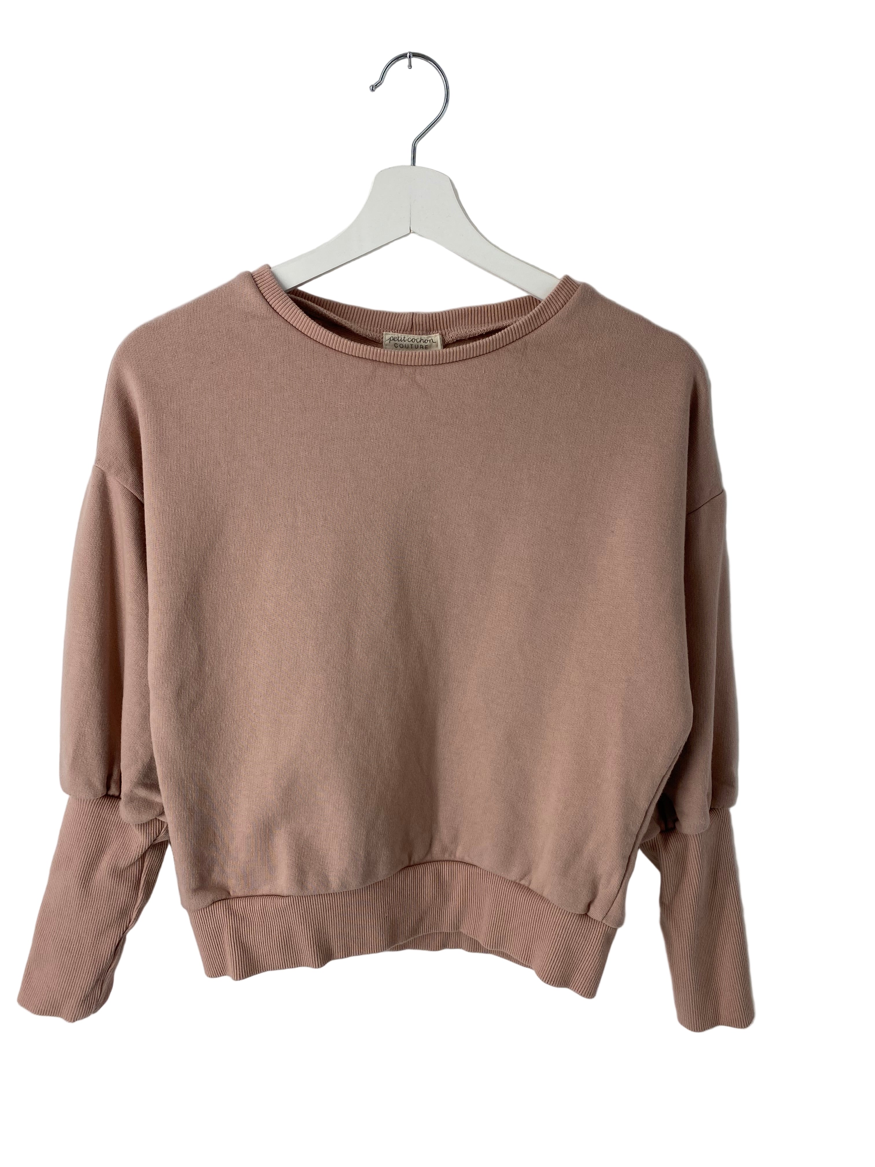 Kopie Frauen Pumppulli Bio-Sweat Puder Gr XS: Ein leicht gekürzter, langärmeliger Pullover mit Rundhalsausschnitt, überschnittenen Schultern sowie gerippten Bündchen und Saum, präsentiert auf einem weißen Holzkleiderbügel. Zustand: gut.