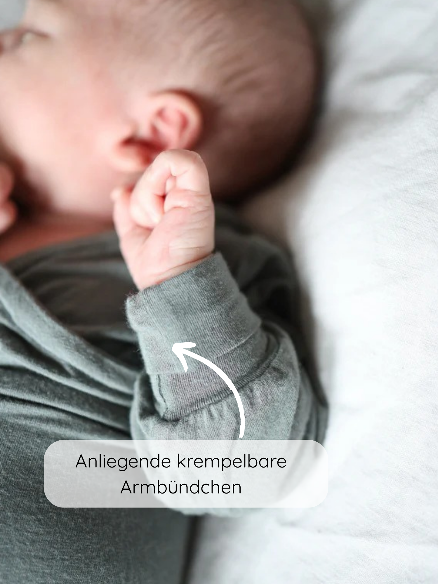 Loopbody Kaschmir-Mix - Taube: Nahaufnahme eines Babys in einem weichen, grünen Einteiler mit anliegenden, krempelbaren Armbündchen, die Wärme bieten und mit dem Baby mitwachsen.