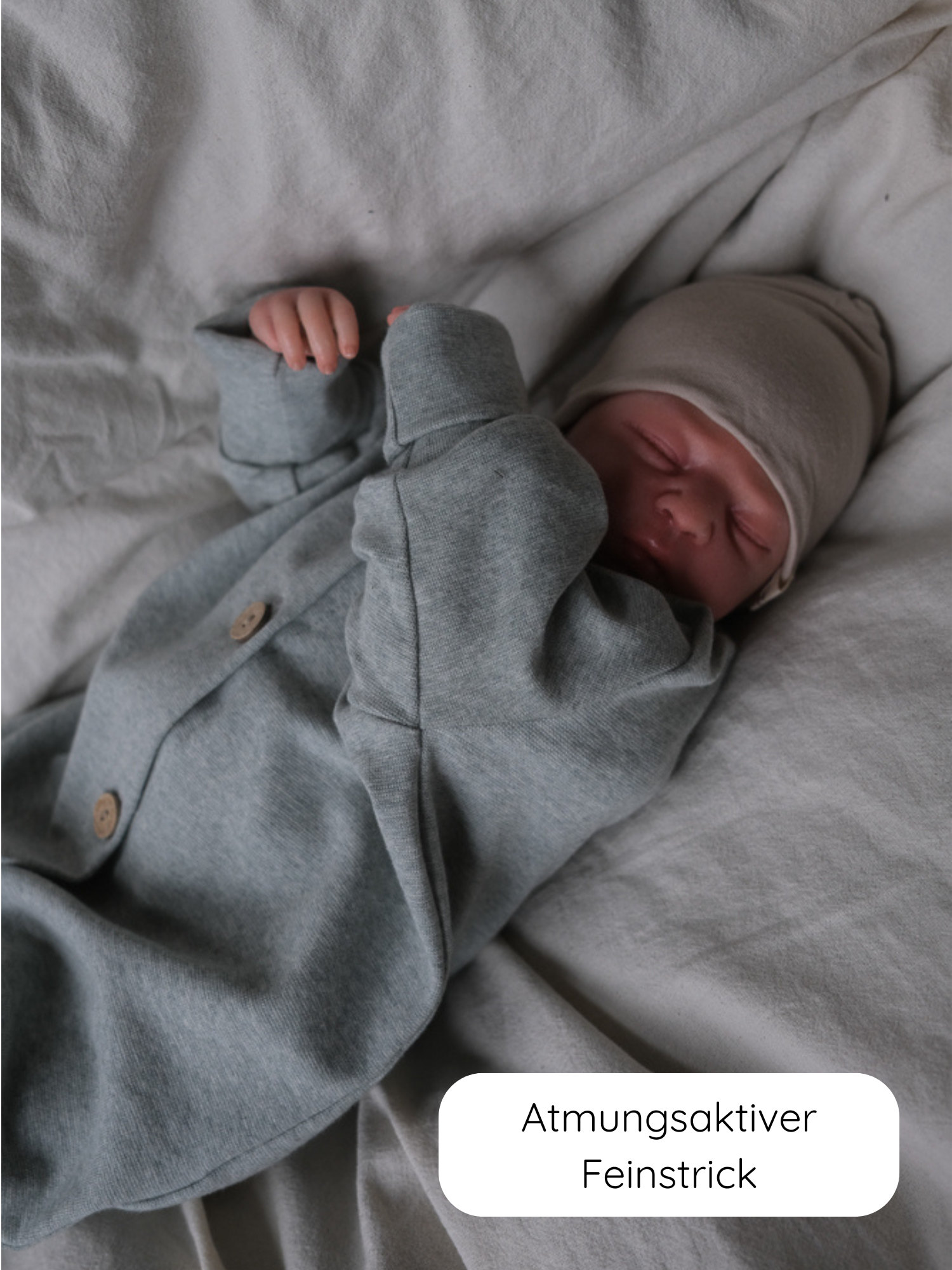 Neugeborenes in Mini Overall Feinstrick - Mint Meliert, weicher grauer Strick mit Holzknöpfen. Atmungsaktiver Feinstrick, ideal zum Schlafen. Beige Mütze ergänzt den gemütlichen Look.