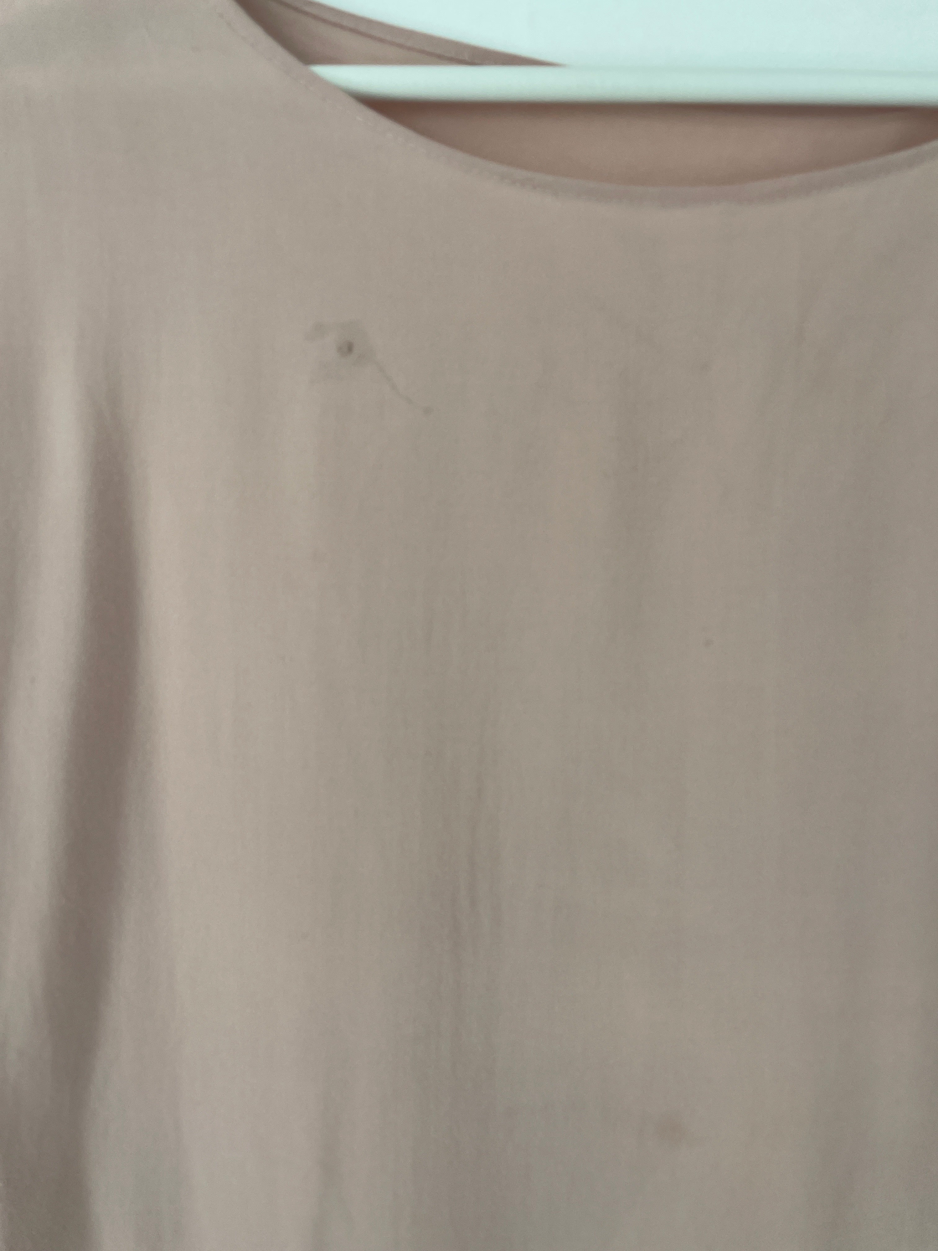 Nahaufnahme des Shirt Viskose Rosé Gr. S mit rundem Ausschnitt, auf weißem Bügel hängend. Einfache, ungemusterte Oberfläche, Zustand: okay, fleckig.