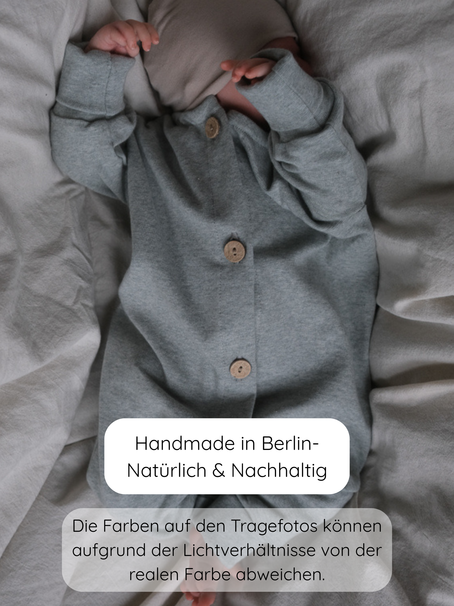 Ein Baby liegt auf einem Bett in einem Mini Overall Feinstrick - Mint Meliert, mit Holzknöpfen, handgefertigt in Berlin aus weichem, dehnbarem Feinstrick-Jersey für Komfort und Bewegungsfreiheit.