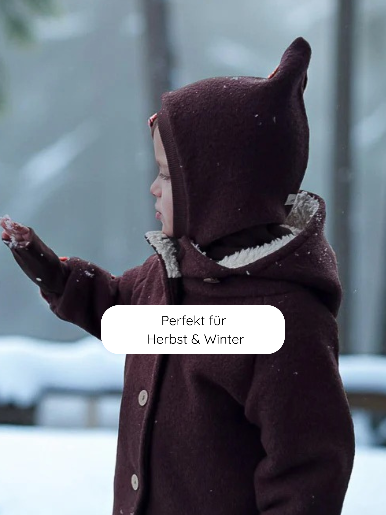 Kind im Profil im Schnee trägt eine dunkle Schlupfmütze Wollwalk - Schoko mit flauschigem Innenfutter, das Kopf und Hals wärmt. Perfekt für kalte Tage, atmungsaktiv und bequem.