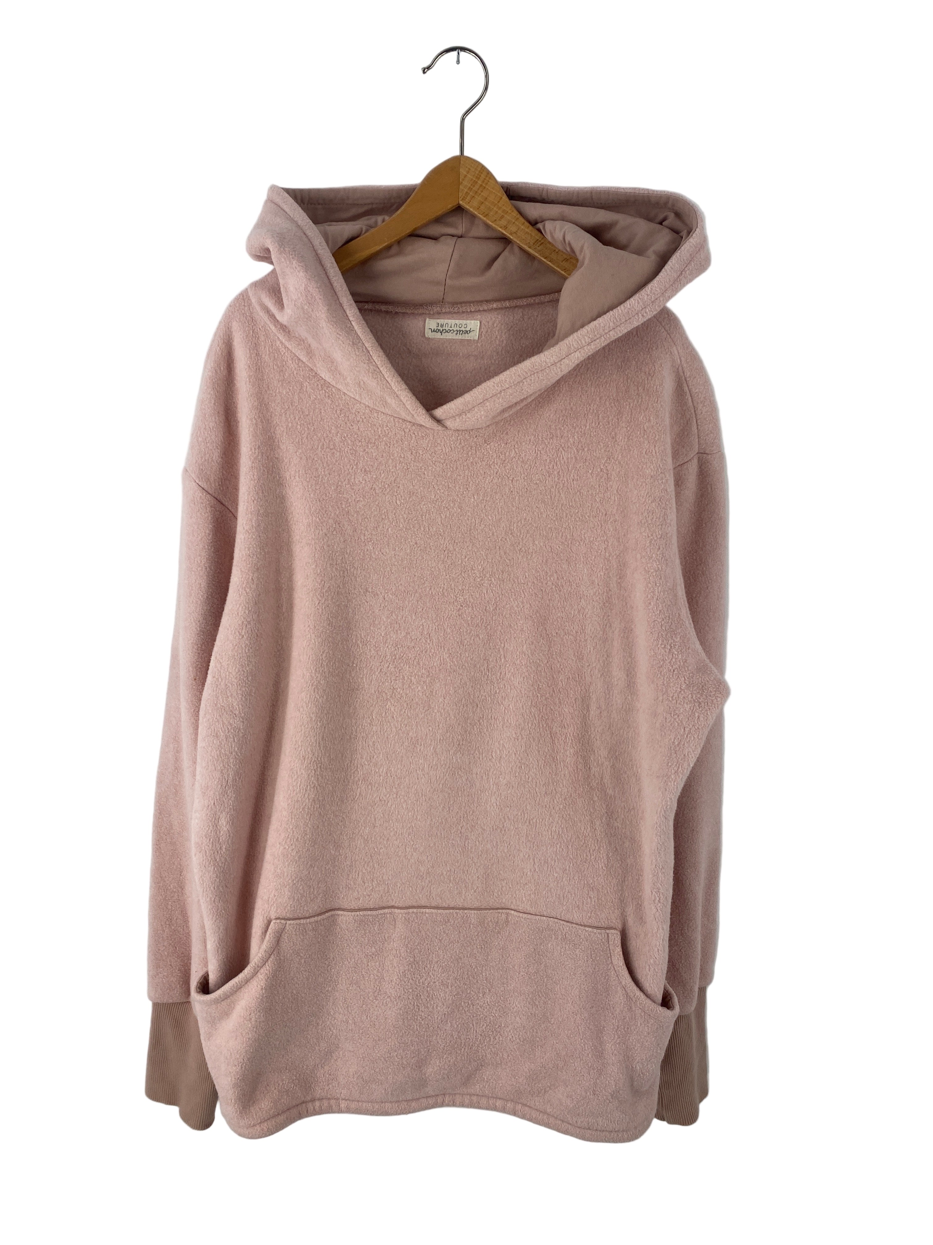 Ein weicher Rock Bio Musselin Puder Gr 4/5Y in staubigem Rosa, mit Kapuze, überschnittenen Schultern, gerippten Bündchen und einer Kängurutasche, hängt an einem Holzbügel. Zustand: sehr gut.