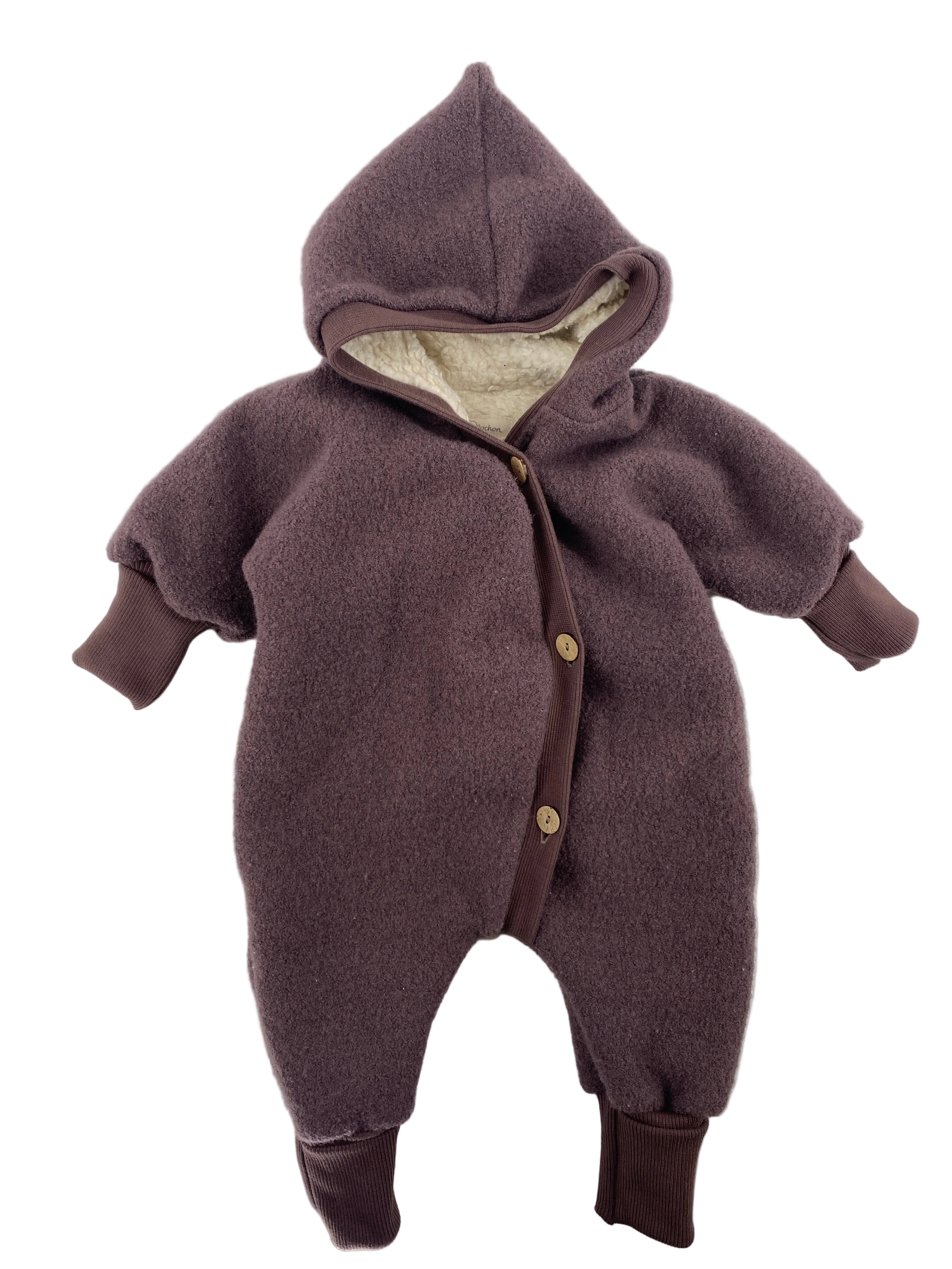 Der Winteroverall Wollwalk Malve mit Teddyfutter Gr 0M zeigt einen einteiligen, kapuzenbehafteten Baby-Strampler aus weichem Fleece, mit durchgehender Knopfleiste, gerippten Bündchen und gefütterter Kapuze, ideal für kalte Tage.