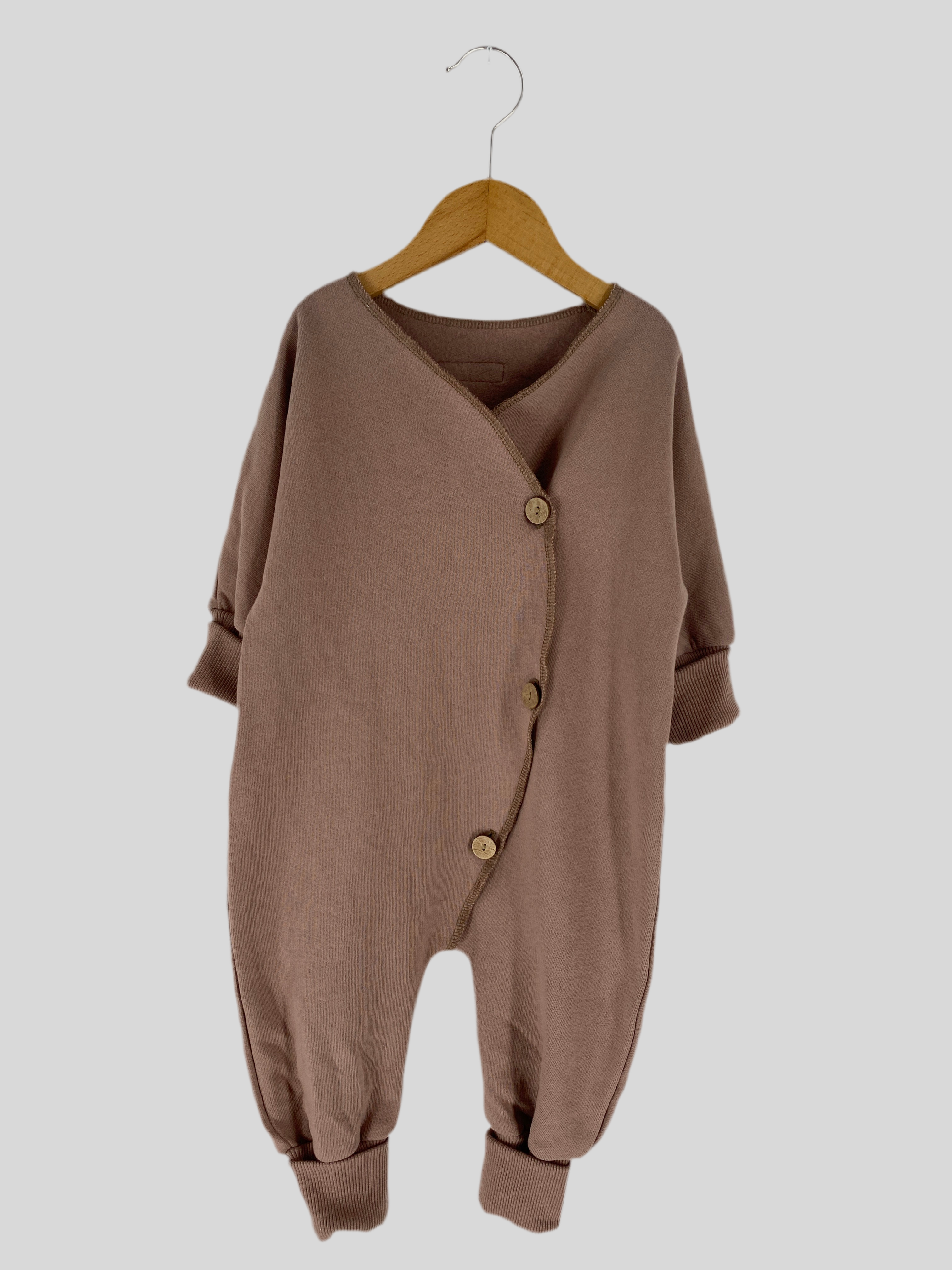 NEU Mini Overall Bio-Sweat Puder Gr 6M: Braunes gestricktes Baby-Outfit mit Knöpfen auf einem Holzschaukelstuhl, präsentiert als stilvoller und komfortabler Strampler für Babys. Zustand: neu.