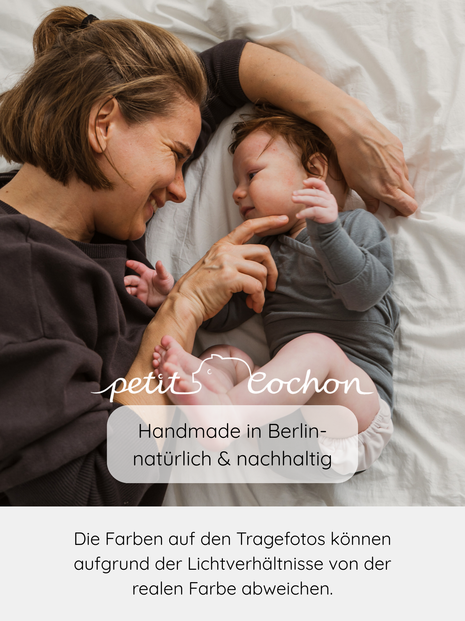 Mutter berührt lächelnd das Kinn ihres Babys, das einen Loopbody Kaschmir-Mix - Taube in Grau trägt. Beide schauen sich an, während das petit cochon-Logo sichtbar ist.