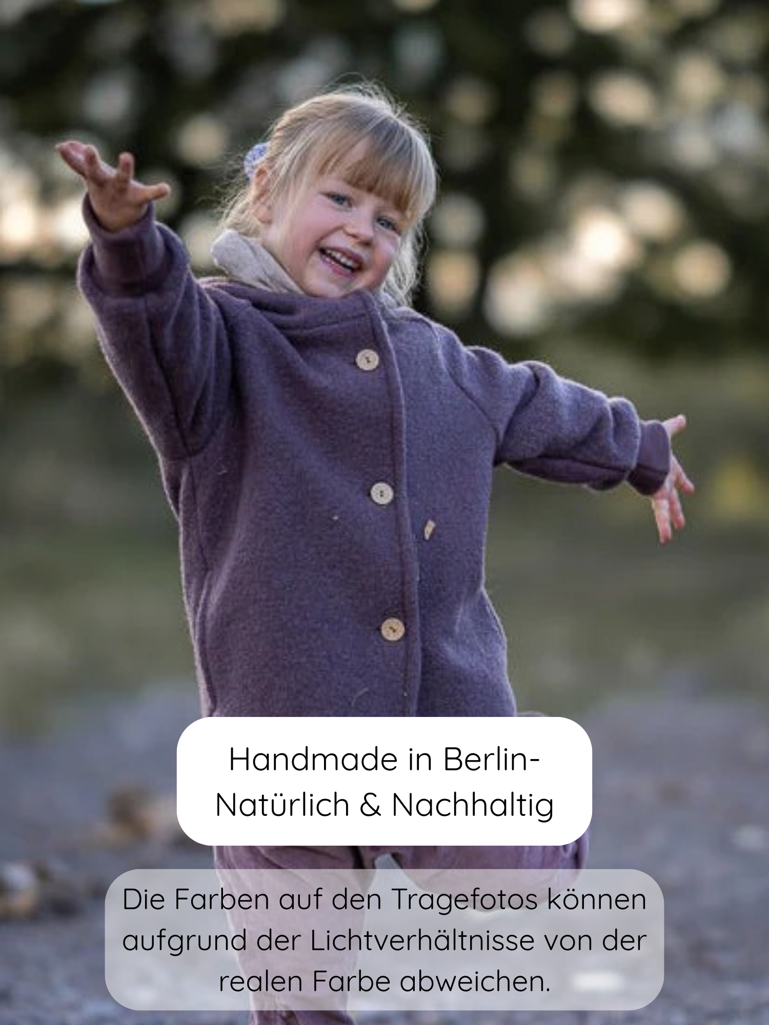 Junges Mädchen im Freien, lächelnd mit ausgestreckten Armen, trägt die Wichteljacke Wollwalk - Malve. Die lila Jacke hat einen Knopfverschluss und ist perfekt für kühle Jahreszeiten.