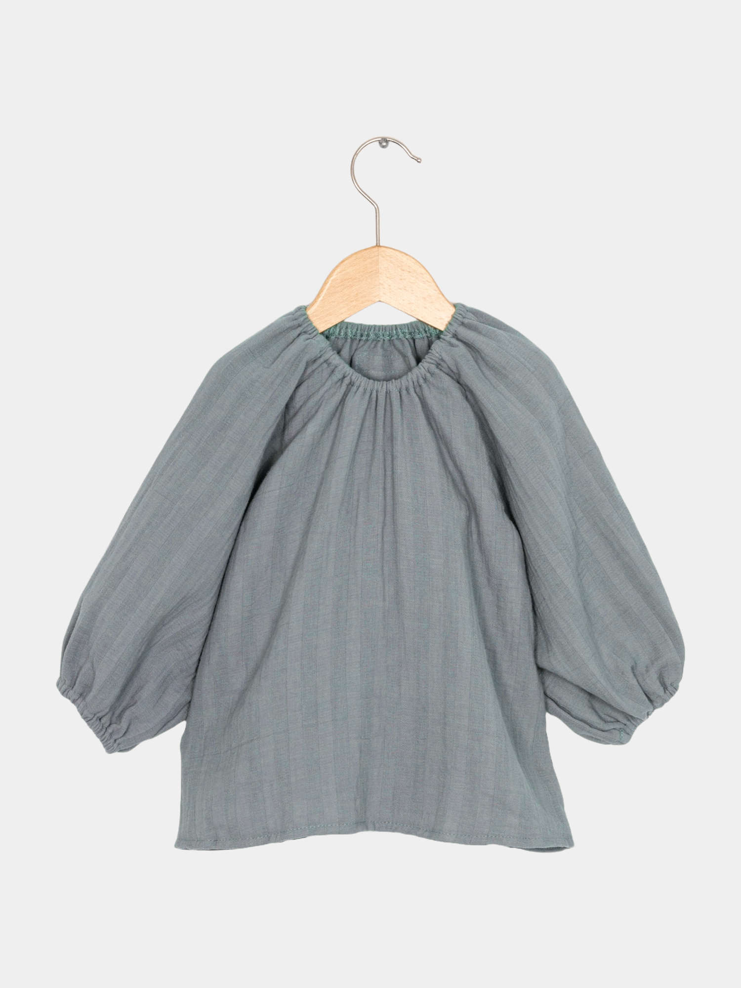 Das Blüschen Musselin - Eisblau ist ein handgefertigtes, leichtes Oberteil aus weichem Musselin, ideal für verschiedene Jahreszeiten. Sein mitwachsender Schnitt ermöglicht vielseitiges Tragen von Kleid bis Bluse.