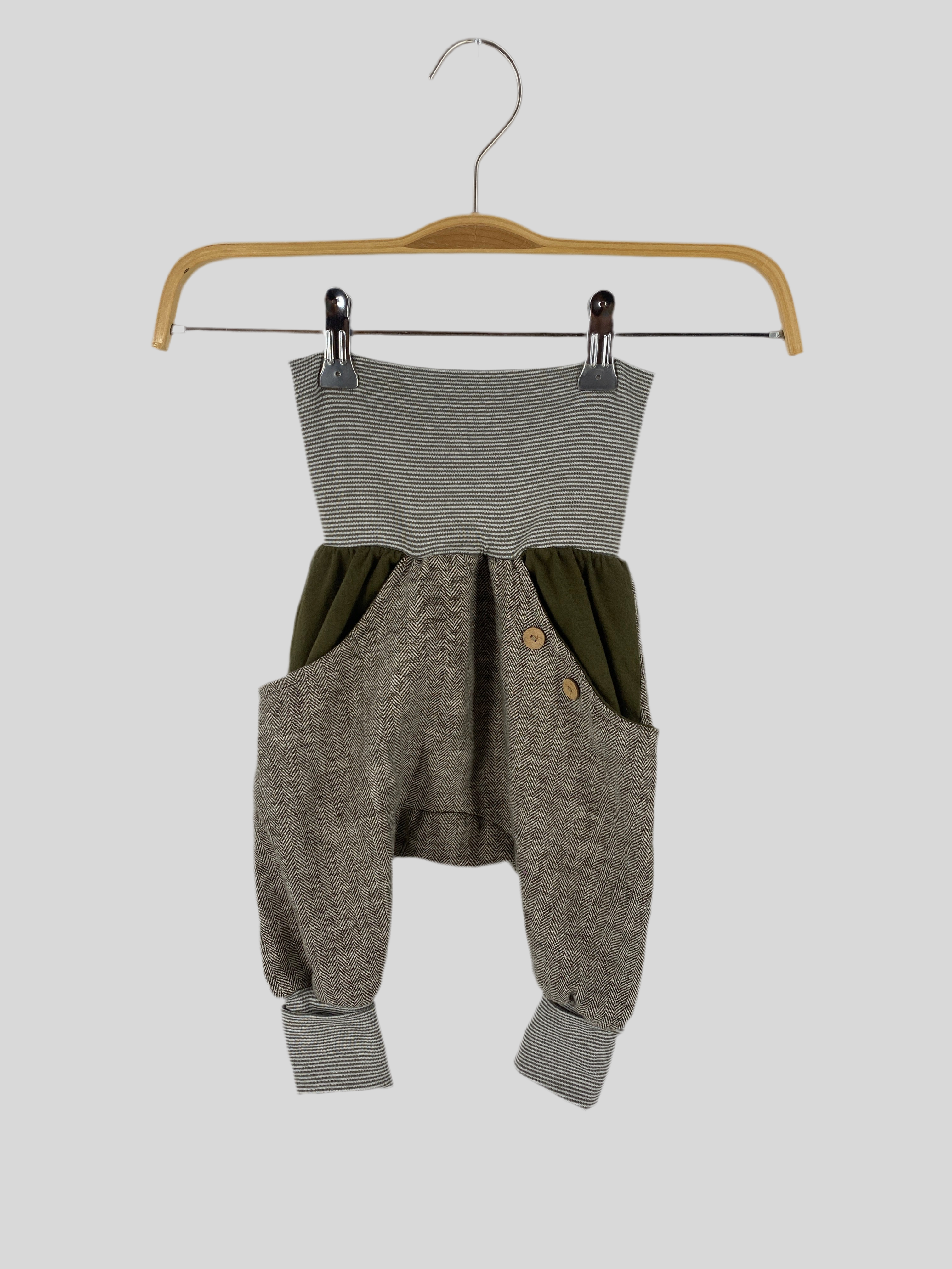 (Kopie) Knickerbocker Fischgrat Avocado Gr 1Y zeigt eine Nahaufnahme eines modischen Stücks auf einem Holzbügel, das handwerkliche Kunst mit einem Hauch von Struktur und Eleganz verkörpert. Zustand: sehr gut.