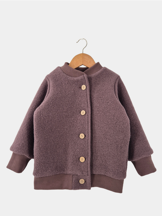 Bomberjacke Wollwalk - Malve, eine Kinderjacke aus Wollwalk mit Knöpfen, auf einem Bügel hängend, zeigt Details wie braune Strickärmel und Holzknöpfe.