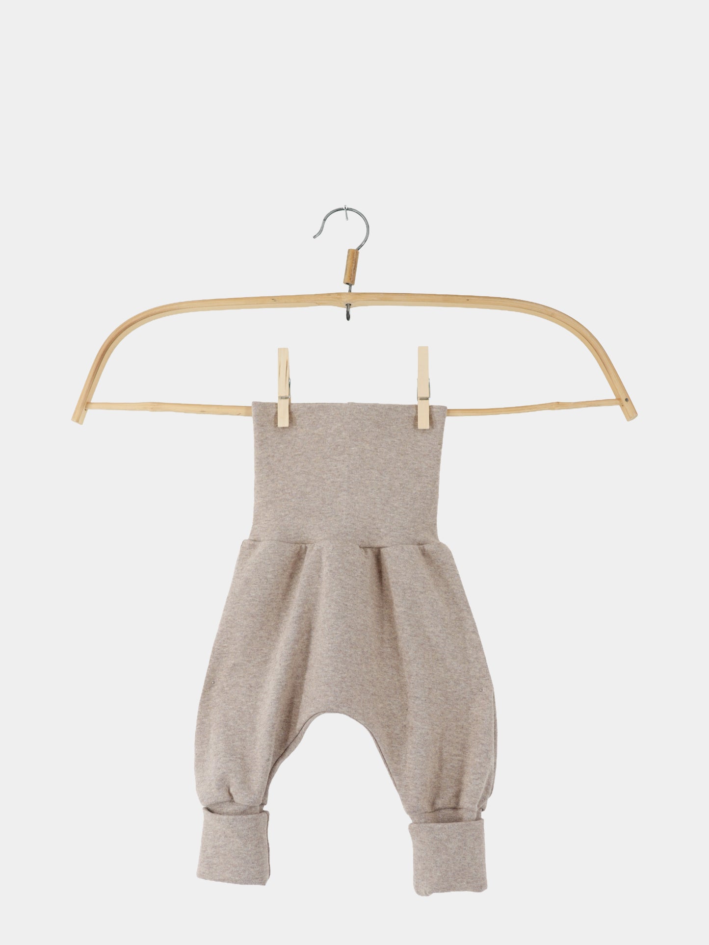Babyknicker Feinstrick - Hafer Meliert: Ein leichter, drop-crotch Babystrampler aus meliertem Feinstrick-Jersey mit breitem, umklappbarem Bund und Bündchen an den Beinöffnungen, präsentiert auf einem Holzkleiderbügel.