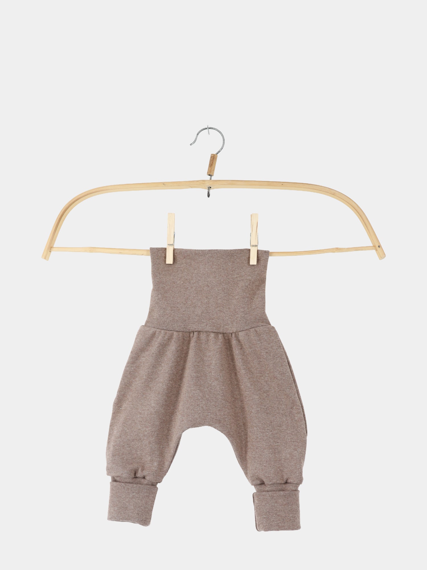 Babyknicker Feinstrick - Praline Meliert: Weiche, braune Babyhose aus elastischem Feinstrick-Jersey mit hohem Bund, tiefem Schnitt und schmalen Bündchen, aufgehängt an einem einfachen Holzbügel mit Metallhaken, vor weißem Hintergrund.