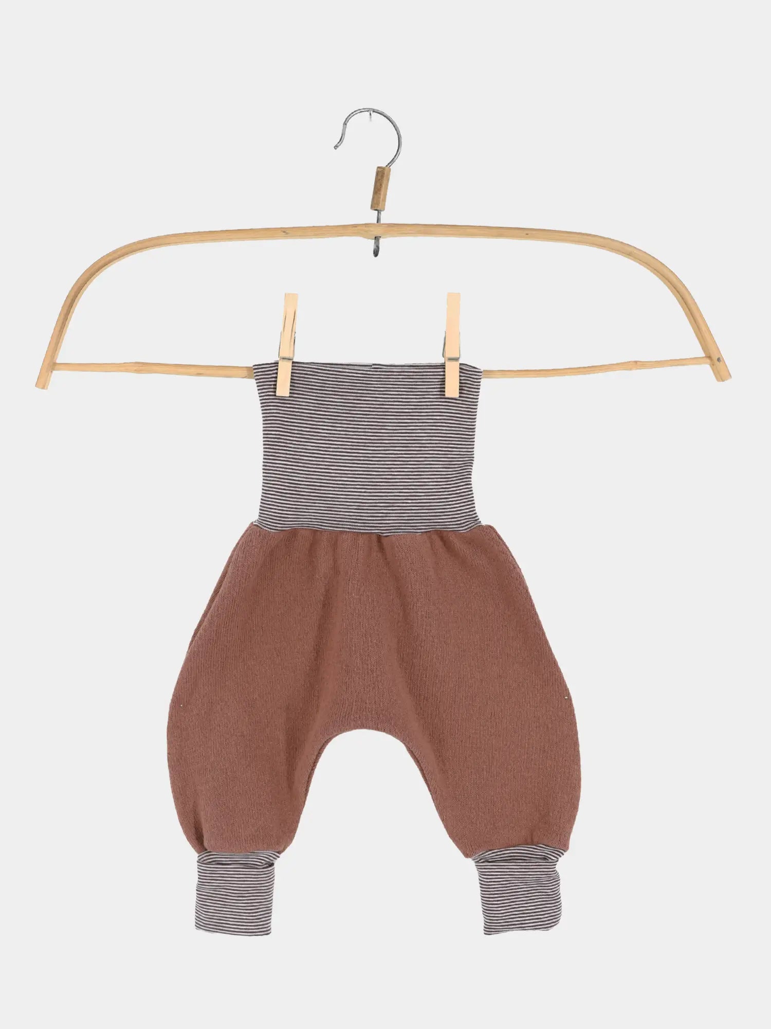Babyknicker Strick - Nougat mit Ringelbündchen zeigt eine locker geschnittene Hose mit grauen Ringelbündchen und terrakottafarbenem Strick, aufgehängt an einem Holzbügel, ideal für Neugeborene.