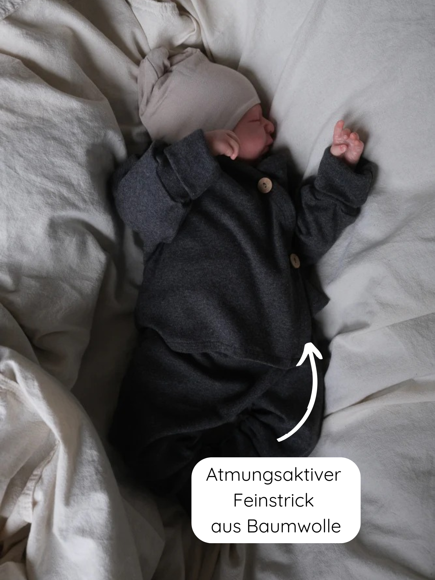 Neugeborenes in Babyschlüttli Feinstrick - Ruß Meliert aus Baumwoll-Jersey mit Holzknöpfen, atmungsaktiv und weich. Das Wickelverschluss-Design erleichtert das Anziehen. Beiges Mützchen vervollständigt das Outfit.
