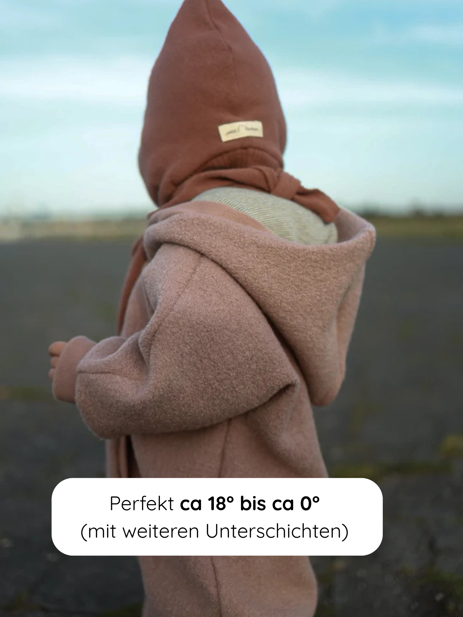 Kleinkind von hinten im Kuschelanzug Wollwalk - Puder, einem weichen Einteiler mit Kapuze und passender Mütze, ideal für Temperaturen von 18 °C bis 0 °C mit zusätzlicher Kleidung.