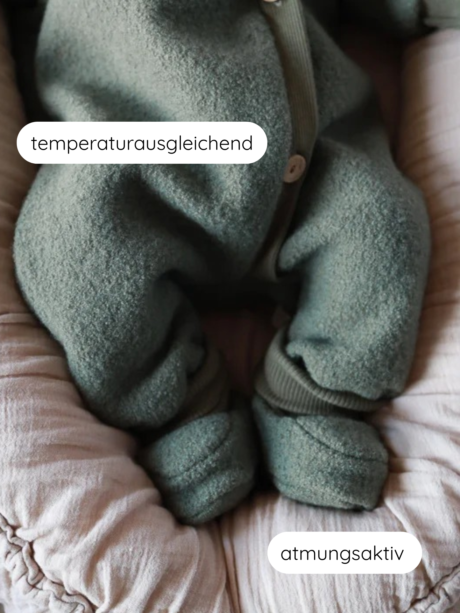 Babybooties Wollwalk - Pistazie: Unterkörper eines Babys in einem moosgrünen Einteiler mit Füßen, auf einem hellrosa Kissen liegend. Eigenschaften: temperaturausgleichend, atmungsaktiv.