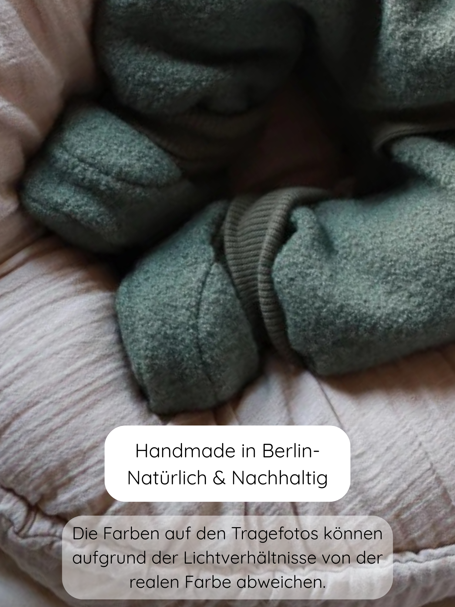 Babybooties Wollwalk - Pistazie: Weiches, grünes Wollwalk-Gewebe, gefaltete Bündchen und Ärmel auf einer rosa Steppdecke. Handgemacht in Berlin, nachhaltig produziert. Ideal für Herbst und Winter, sanft zu Babyfüßen.