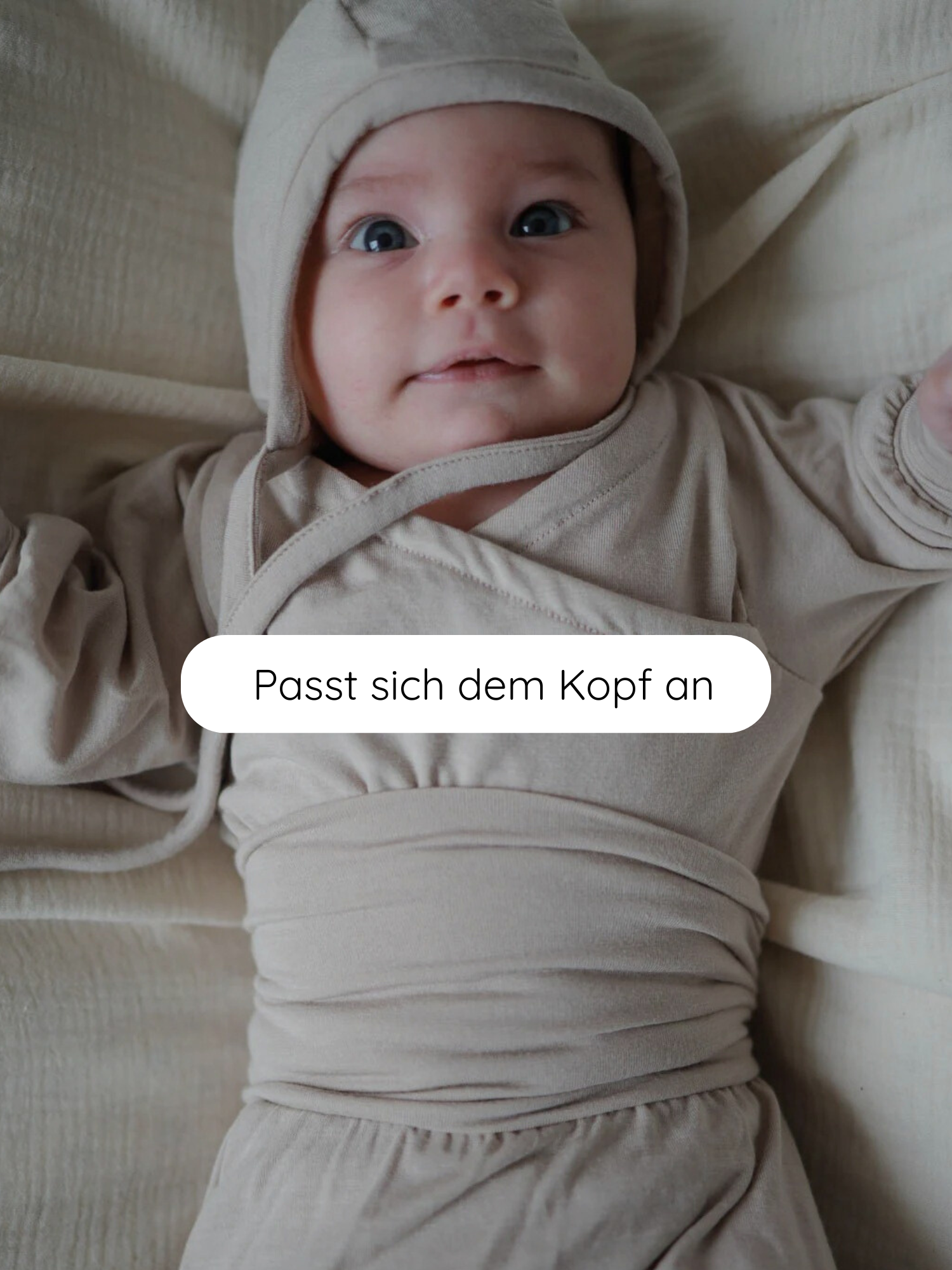 Säugling liegt auf einer beigen Decke, trägt ein Babyhäubchen Kaschmir-Mix - Sand mit passendem Wickelbody. Der Text Passt sich dem Kopf an betont die Anpassungsfähigkeit des Häubchens.