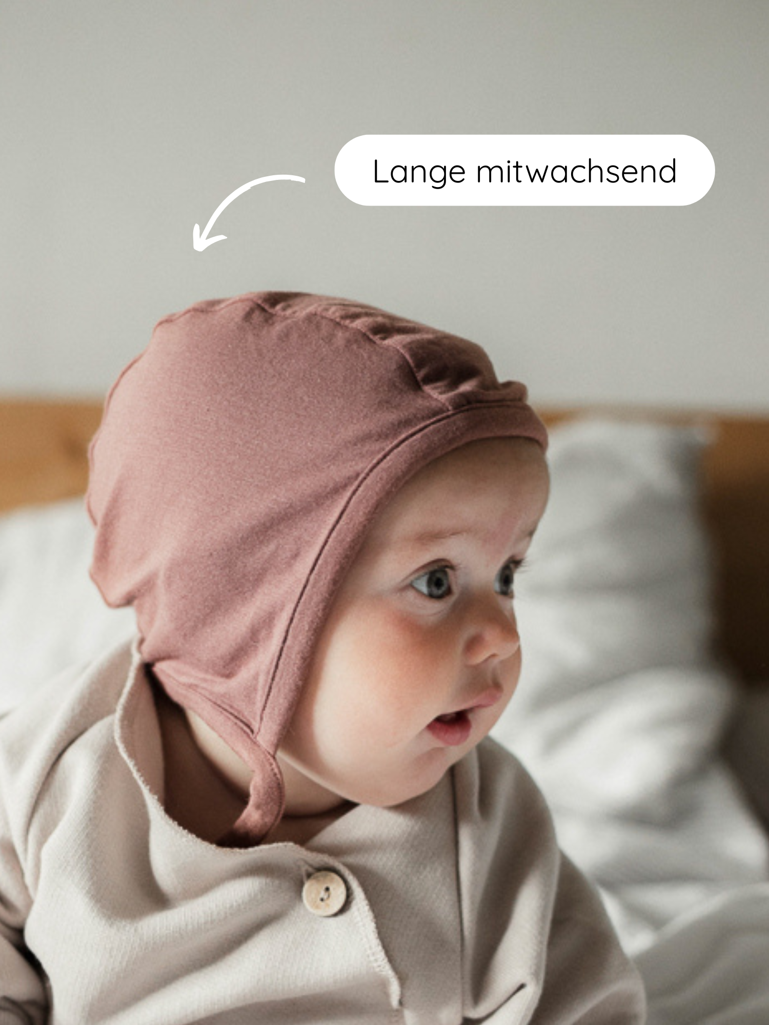 Babyhäubchen Kaschmir-Mix - Zimt auf einem Baby, mit Staubrosen-Bonnet und langen Bändern, die auf die verstellbare, mitwachsende Passform hinweisen, ideal für Wärme und Schutz.