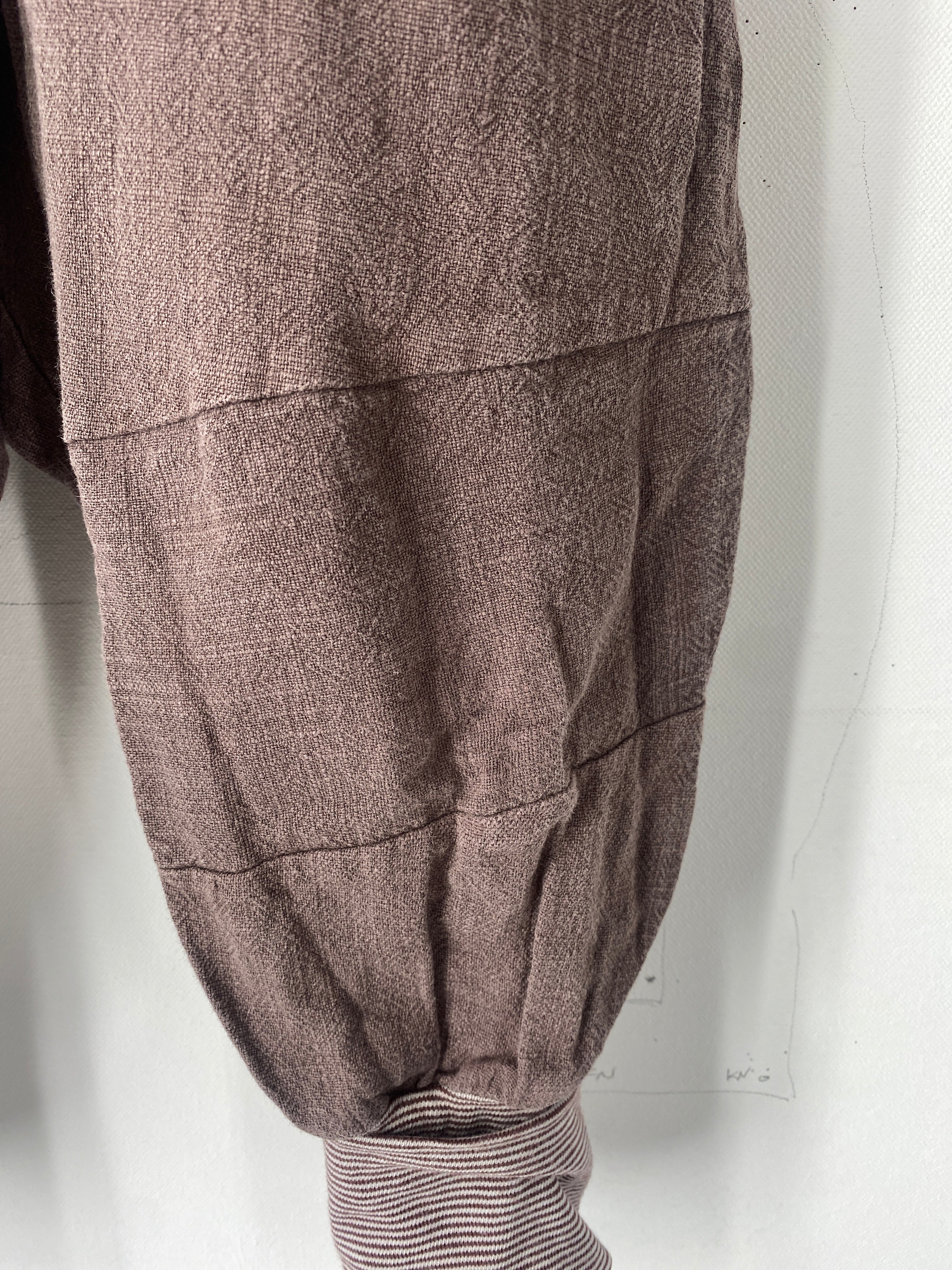 Nahaufnahme der Knickerbocker Leinen Erde Gr 3Y mit horizontalen Nähten und einem gestreiften, gerippten Bund, der darunter hervorschaut. Zustand: gut, mit eingenähten Flicken.