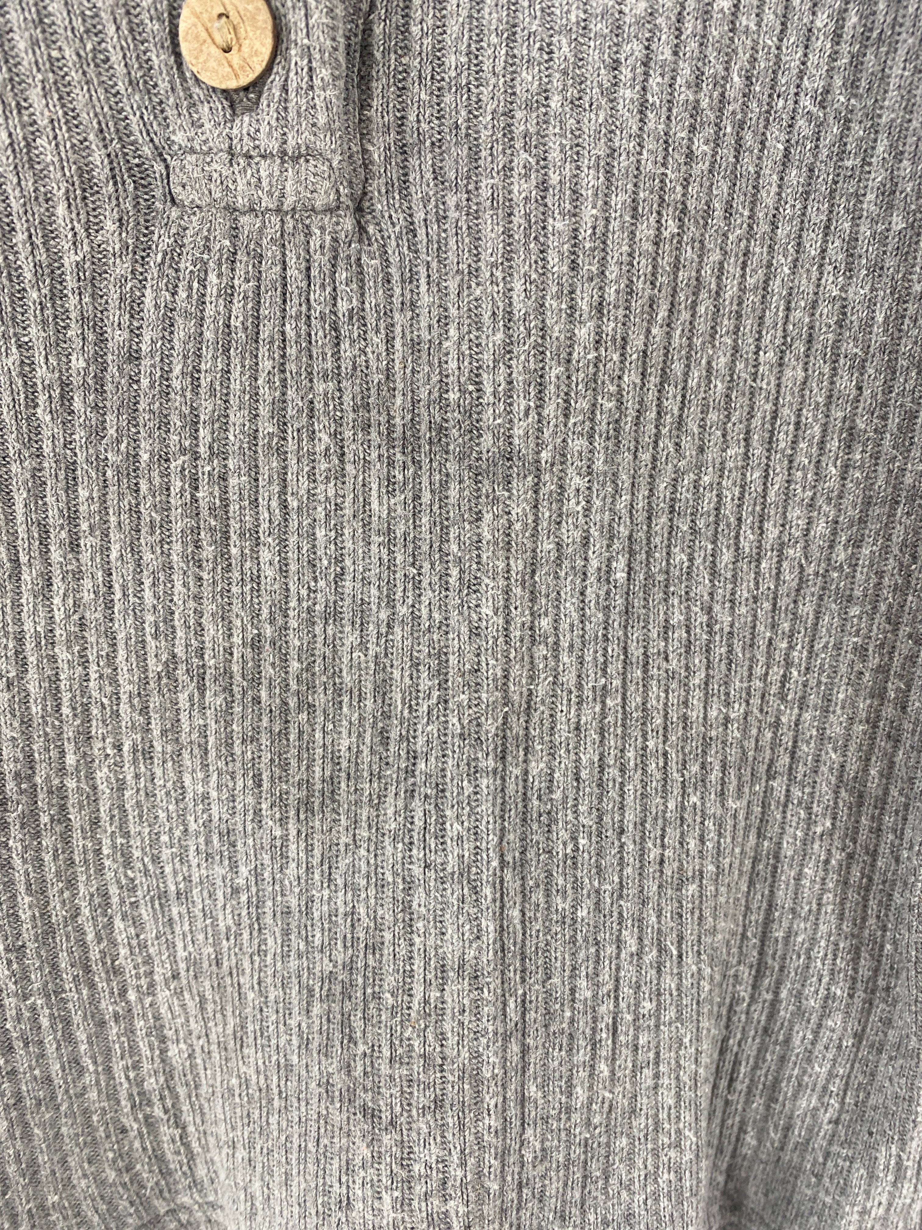 Nahaufnahme des Hemdchen Rippstrick Maus Gr 1Y, ein graues, geripptes Strickoberteil im Henley-Stil mit Holzkopf am Kragen; Zustand gut, leichte Flecken vorne sichtbar.