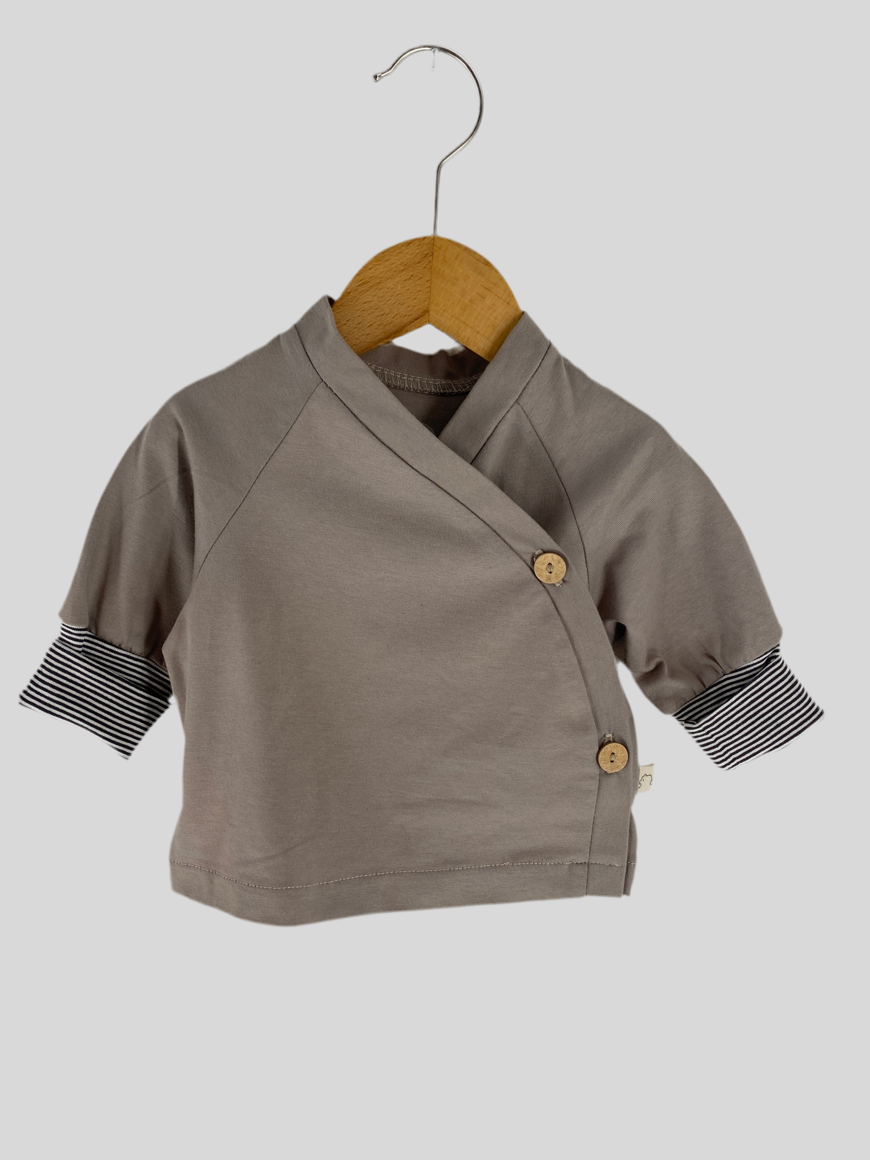 NEU Schlüttli Bio-Jersey Stein Gr 3M, graues Shirt mit schwarz-weißen Streifen, auf Holzstruktur präsentiert. Ideal für Babys, weicher Stoff, modischer Look, perfekt für kühle Tage. Zustand: neu.