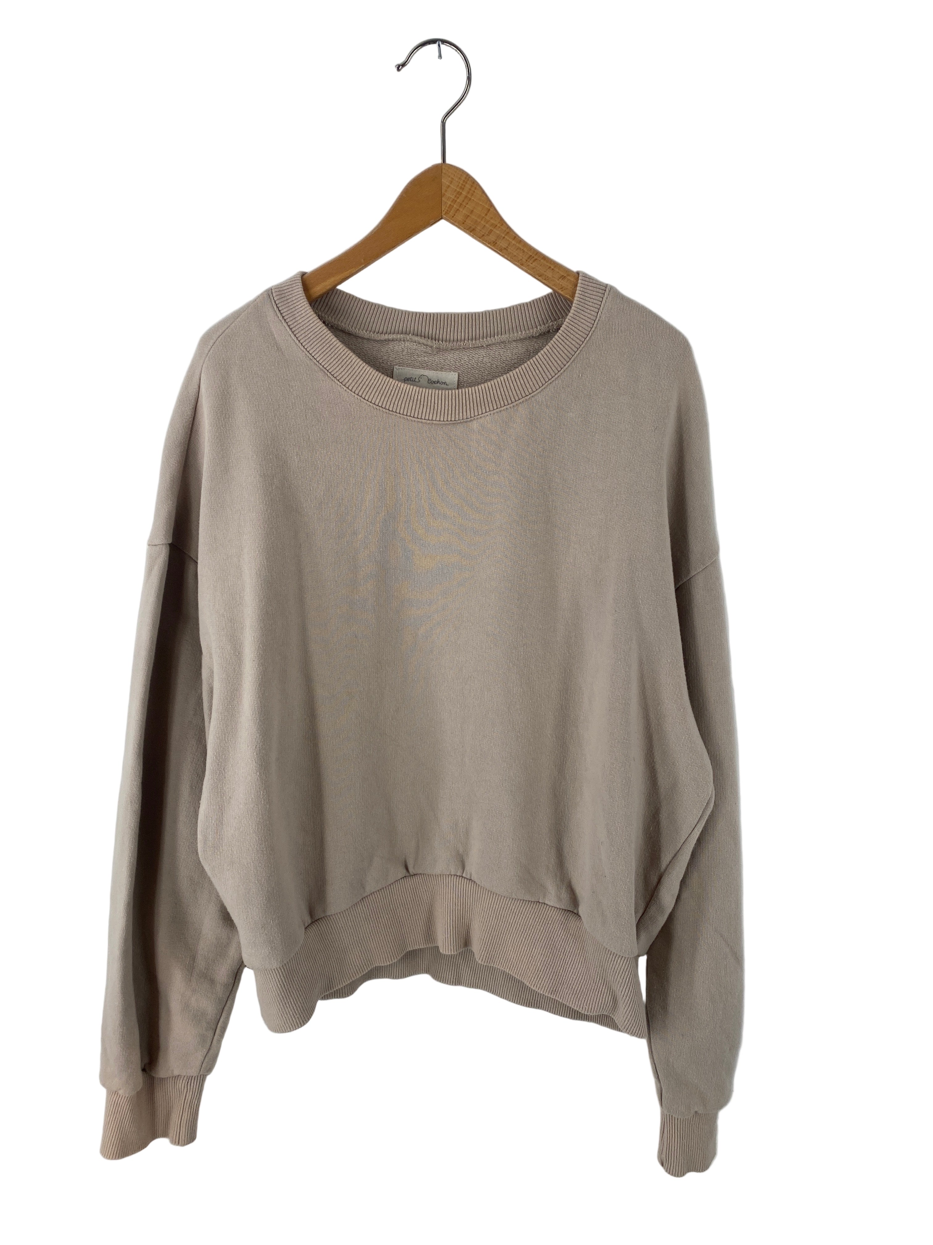 Frauen Pulli kurz Bio Sweat Sand Gr S, ein schlichter Pullover mit Rundhalsausschnitt und langen Ärmeln, leicht fleckig, hängt an einem Holzkleiderbügel vor einem weißen Hintergrund. Zustand: gut.