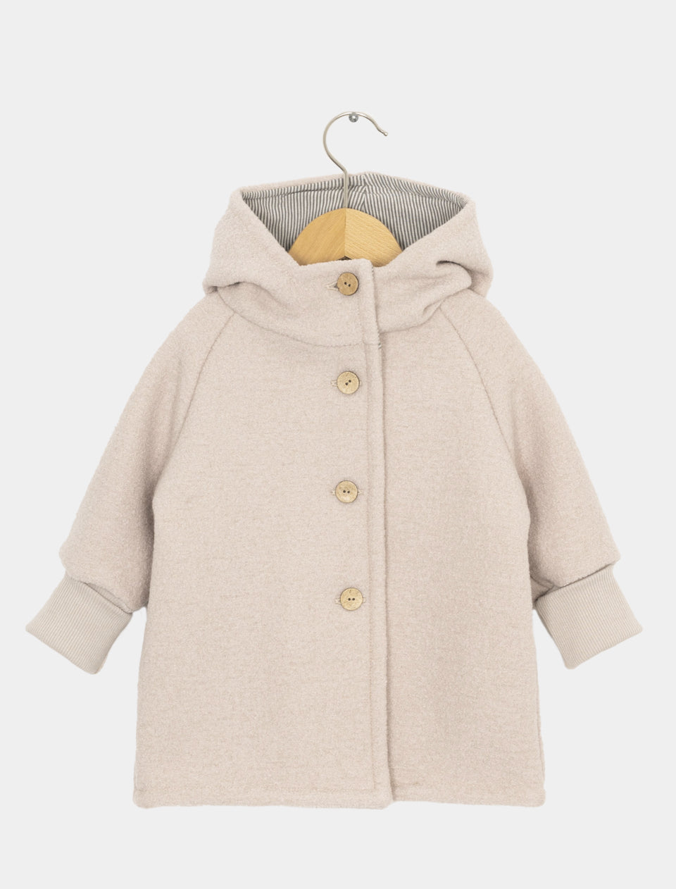 (Kopie) Wichteljacke Wollwalk Sand Gr 10/11Y: Kleine, beige Wolljacke mit Kapuze, Holzknöpfen und gestreiftem Futter. Hängt an Holzbügel, geeignet für Kinder, mit gerippten Bündchen an den Ärmeln.
