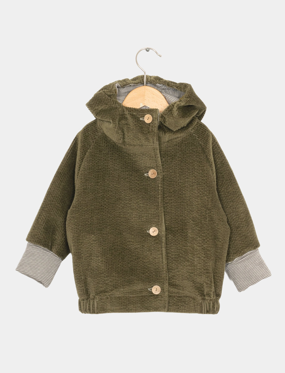Wichteljacke Breitcord Kiwi Gr 6/7: Kinderjacke aus Cord mit Knöpfen, Kapuze und aufgeschlagenen Manschetten, die ein gestreiftes Futter zeigen, präsentiert auf einem Holzbügel vor schlichtem Hintergrund. Zustand: neu.