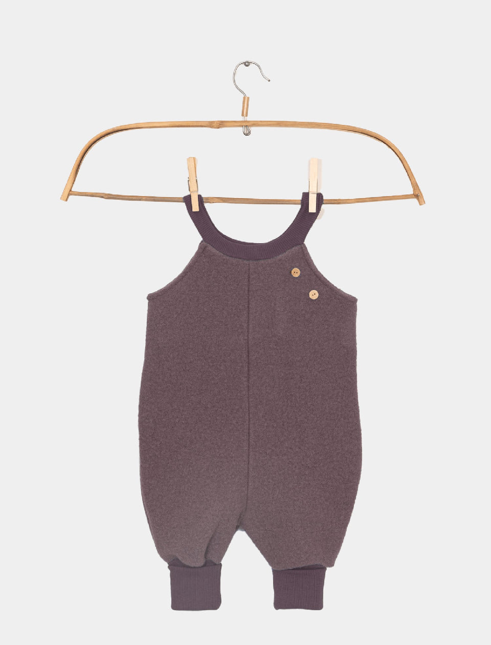 Kopie Schlupflatzhose Wollwalk Malve Gr 2Y: Ein ärmelloser Babystrampler aus weichem Strickstoff mit gerippten Bündchen, Holzknöpfen an der Schulter, auf einem Holzbügel präsentiert. Zustand: neu.