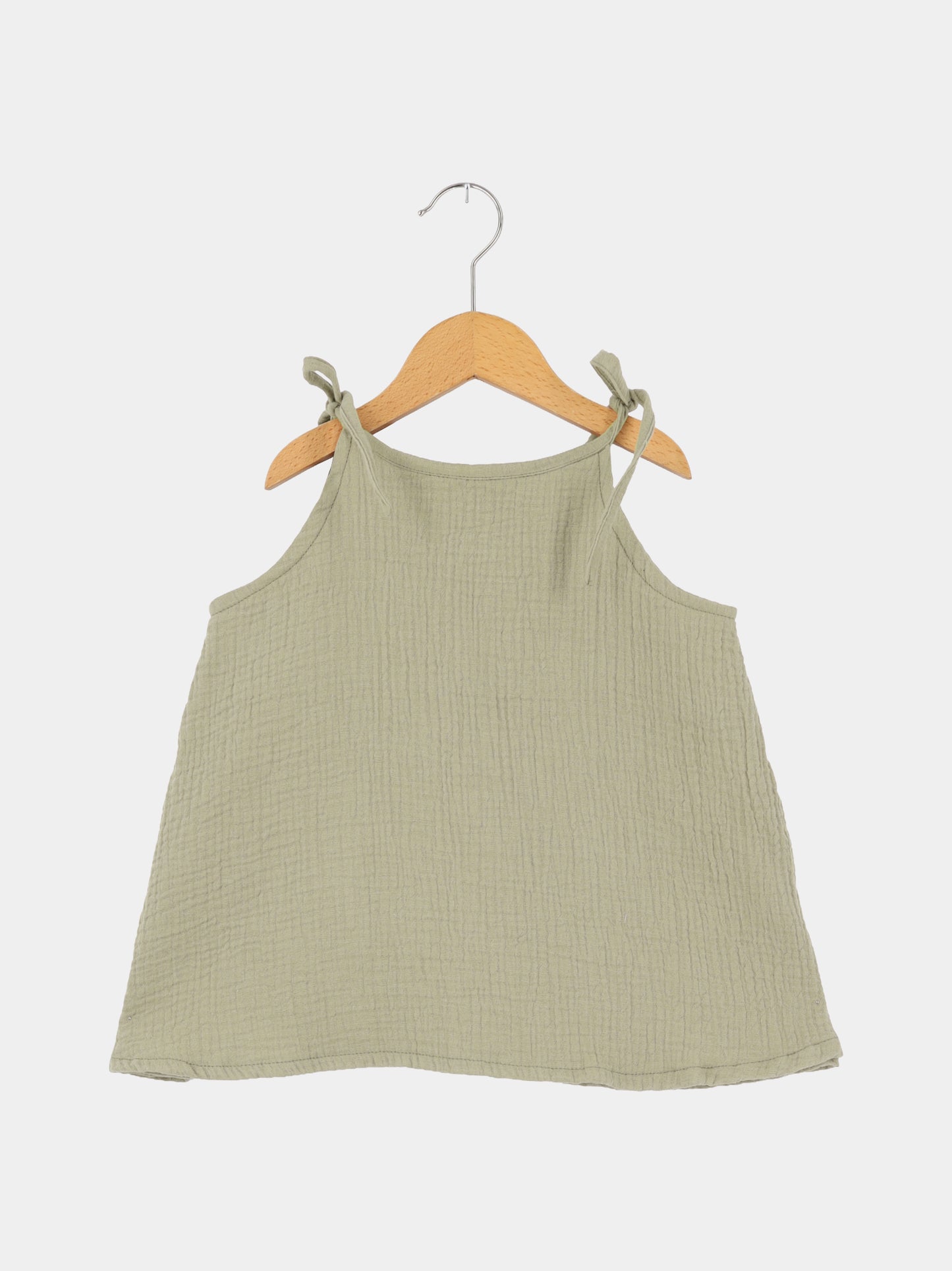 Hängerchen Musselin - Salbei: Ein luftiges, salbeigrünes Musselin-Hängerchen mit verstellbaren Schulterbändern, auf einem Holzkleiderbügel hängend, ideal als wachstumsfähiges Kleid oder Oberteil für Kinder.