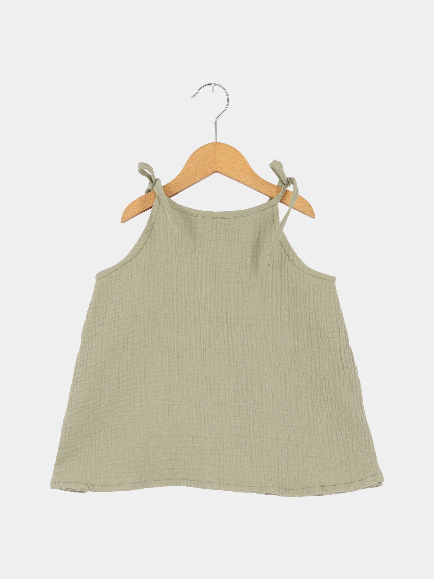 Hängerchen Musselin - Salbei: Ein luftiges, salbeigrünes Musselin-Hängerchen mit verstellbaren Schulterbändern, auf einem Holzkleiderbügel hängend, ideal als wachstumsfähiges Kleid oder Oberteil für Kinder.