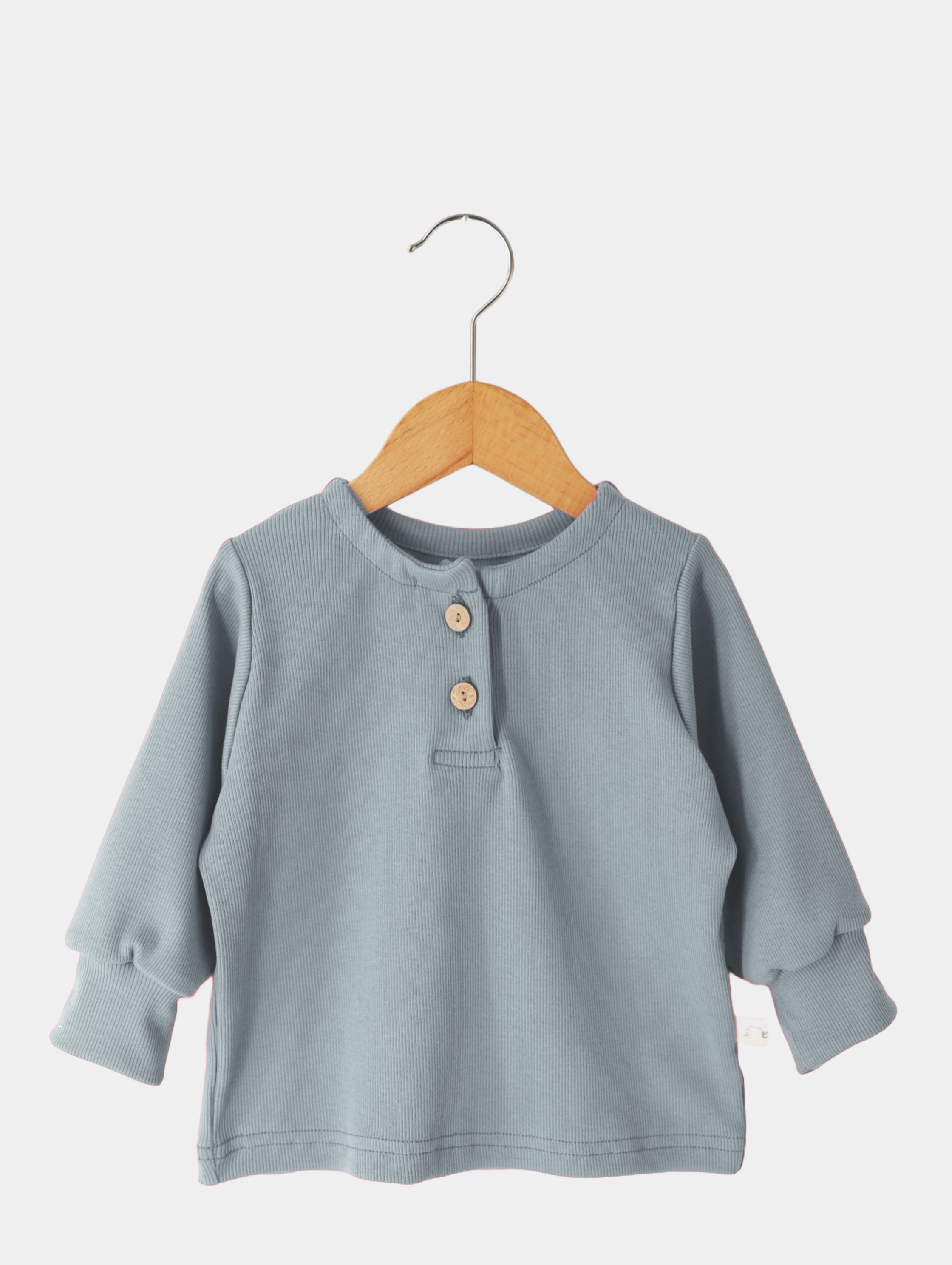 Hemdchen Baumwollripp - Aqua auf einem Holzbügel. Das Shirt zeigt einen nahen Schnitt mit Knöpfen, ideal für Kinder, aus 100% Baumwolle, unisex, für Alltag und besondere Anlässe.